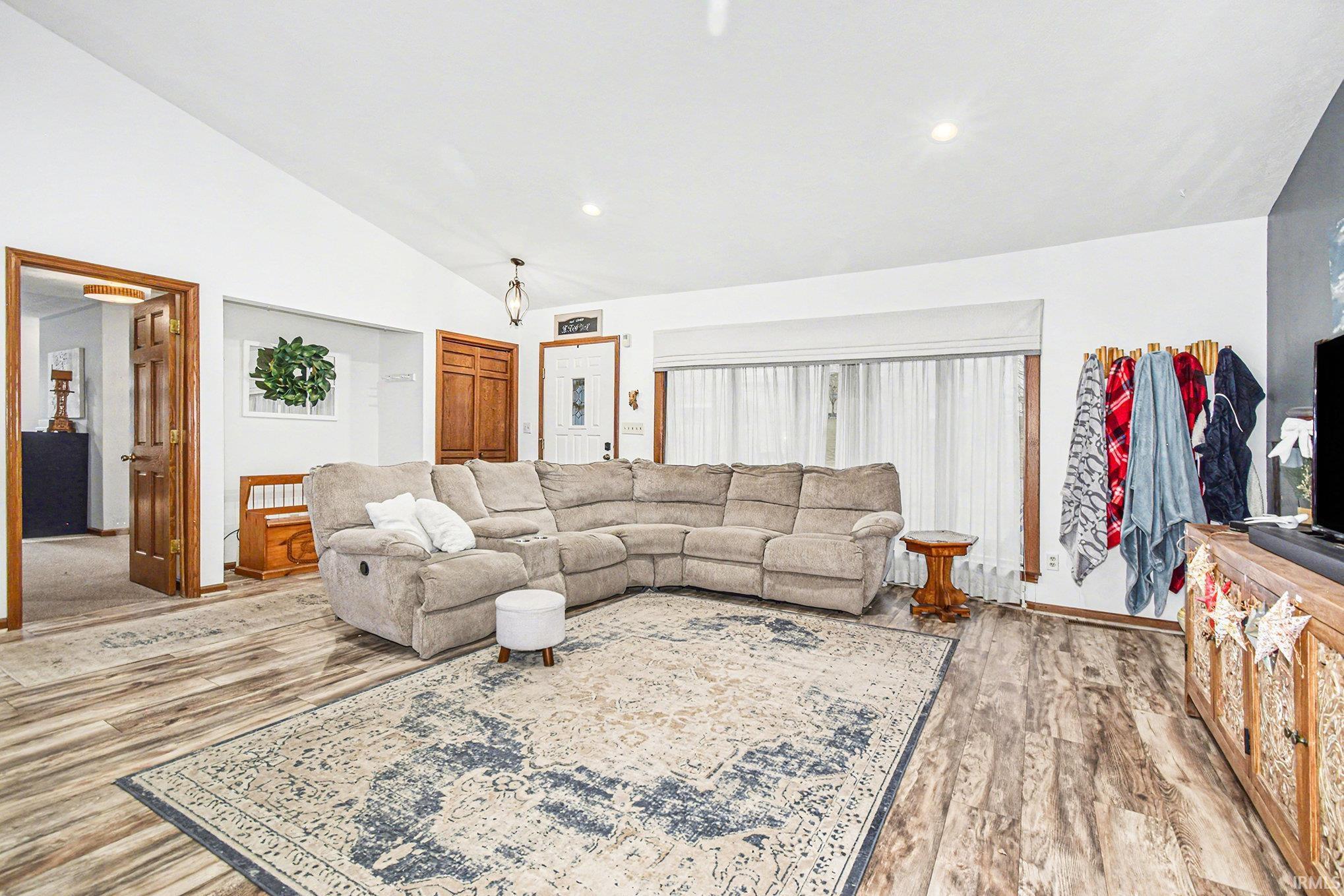 Living area with vaulted ceiling, light wood finished floors, and recessed lighting
