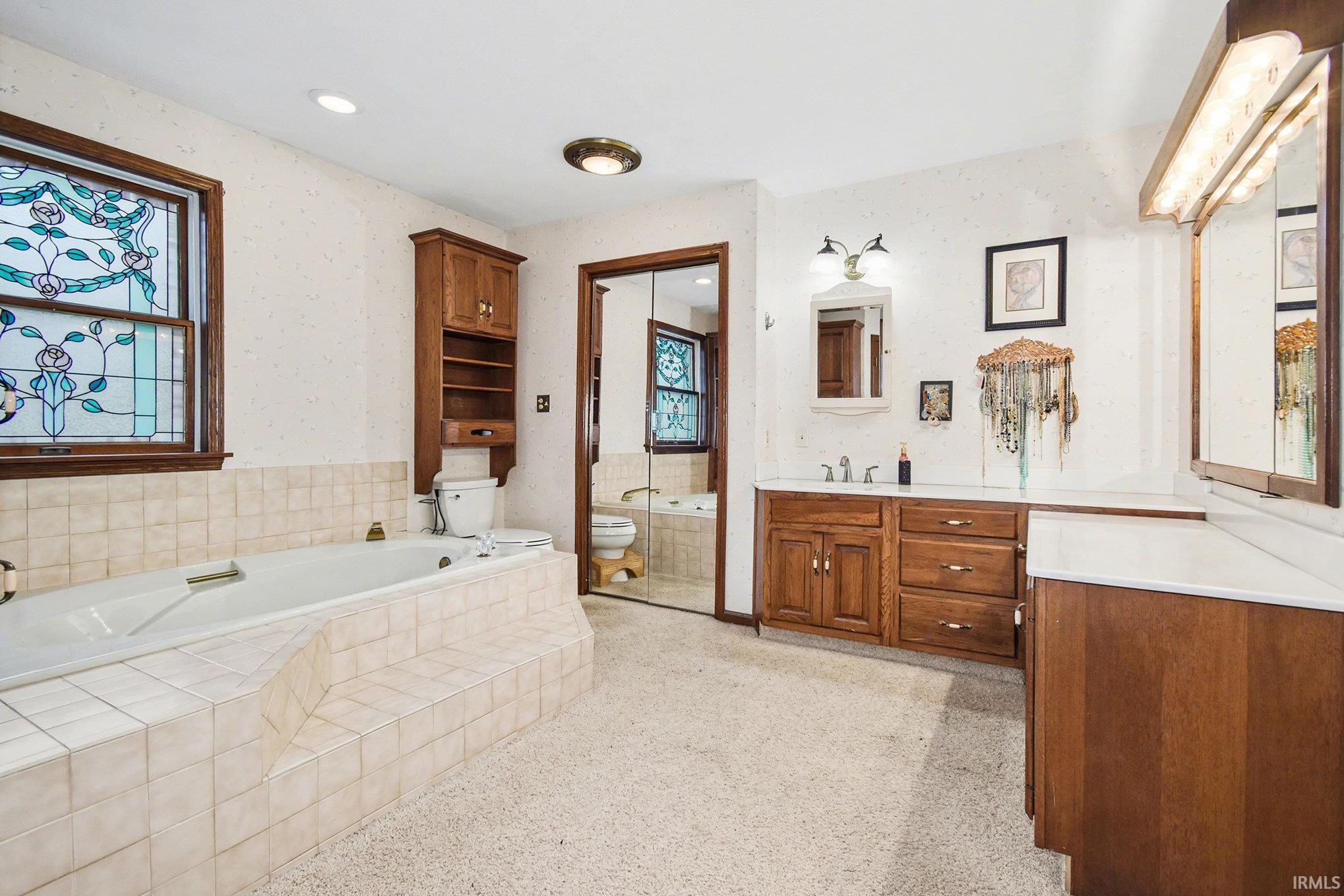 Full bath featuring a garden tub, wallpapered walls, vanity, and recessed lighting