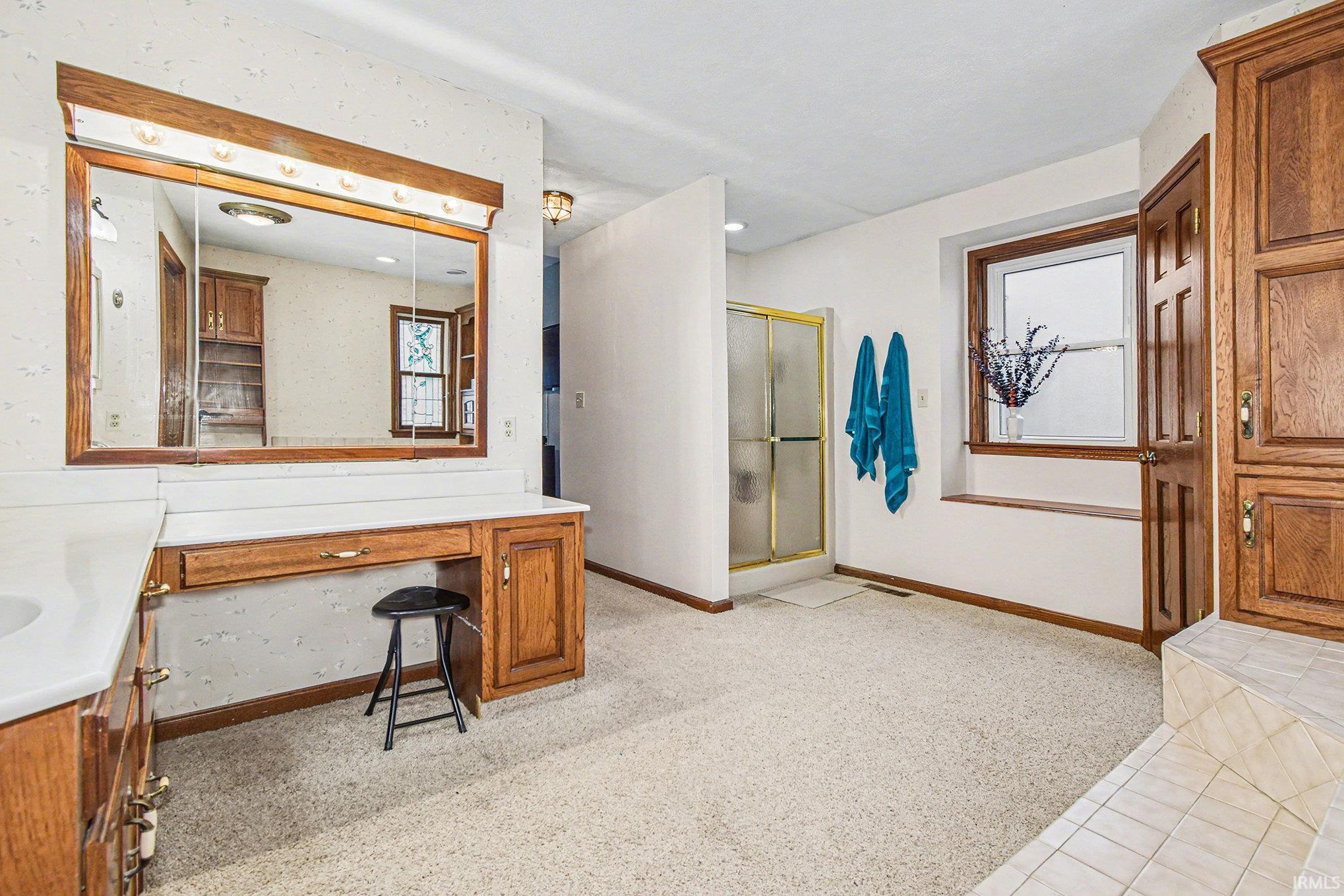 Bathroom with a shower stall, vanity, light carpet, plenty of natural light, and recessed lighting
