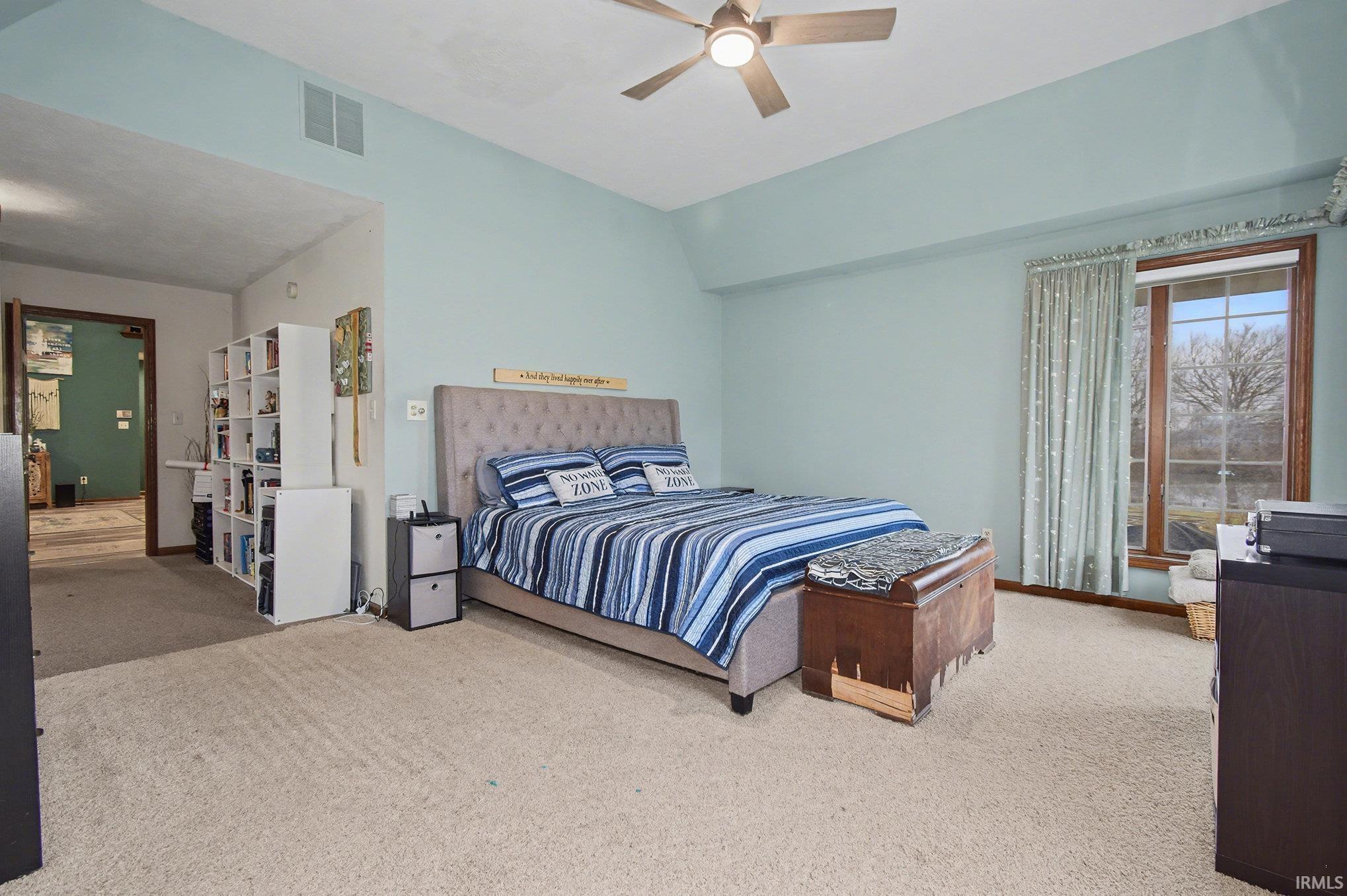 Carpeted bedroom featuring lofted ceiling and ceiling fan