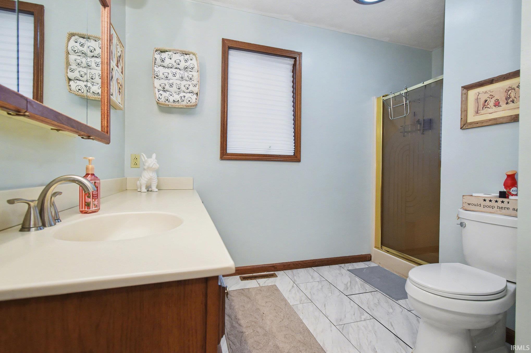 Full bath with vanity, a shower stall, and light marble finish floors