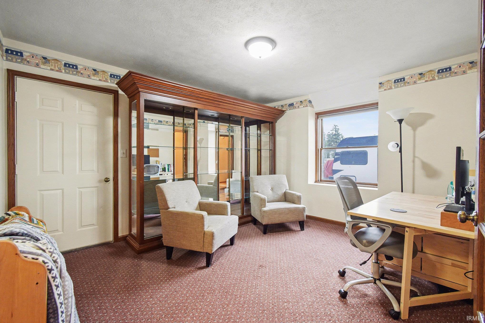 Carpeted office space featuring baseboards and a textured ceiling