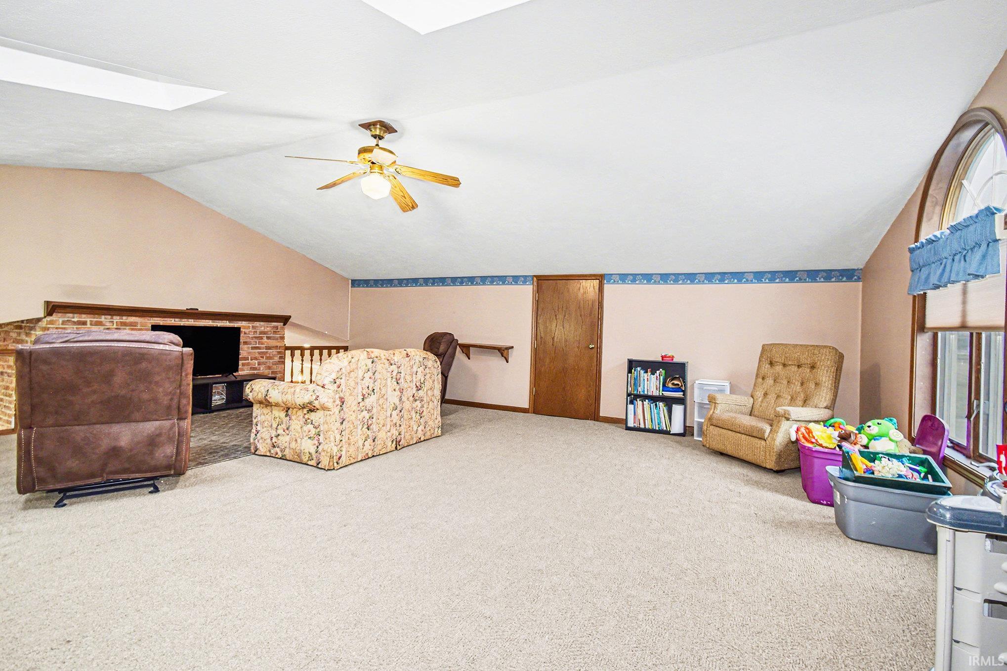 Bedroom featuring lofted ceiling, carpet flooring, a skylight, and a ceiling fan