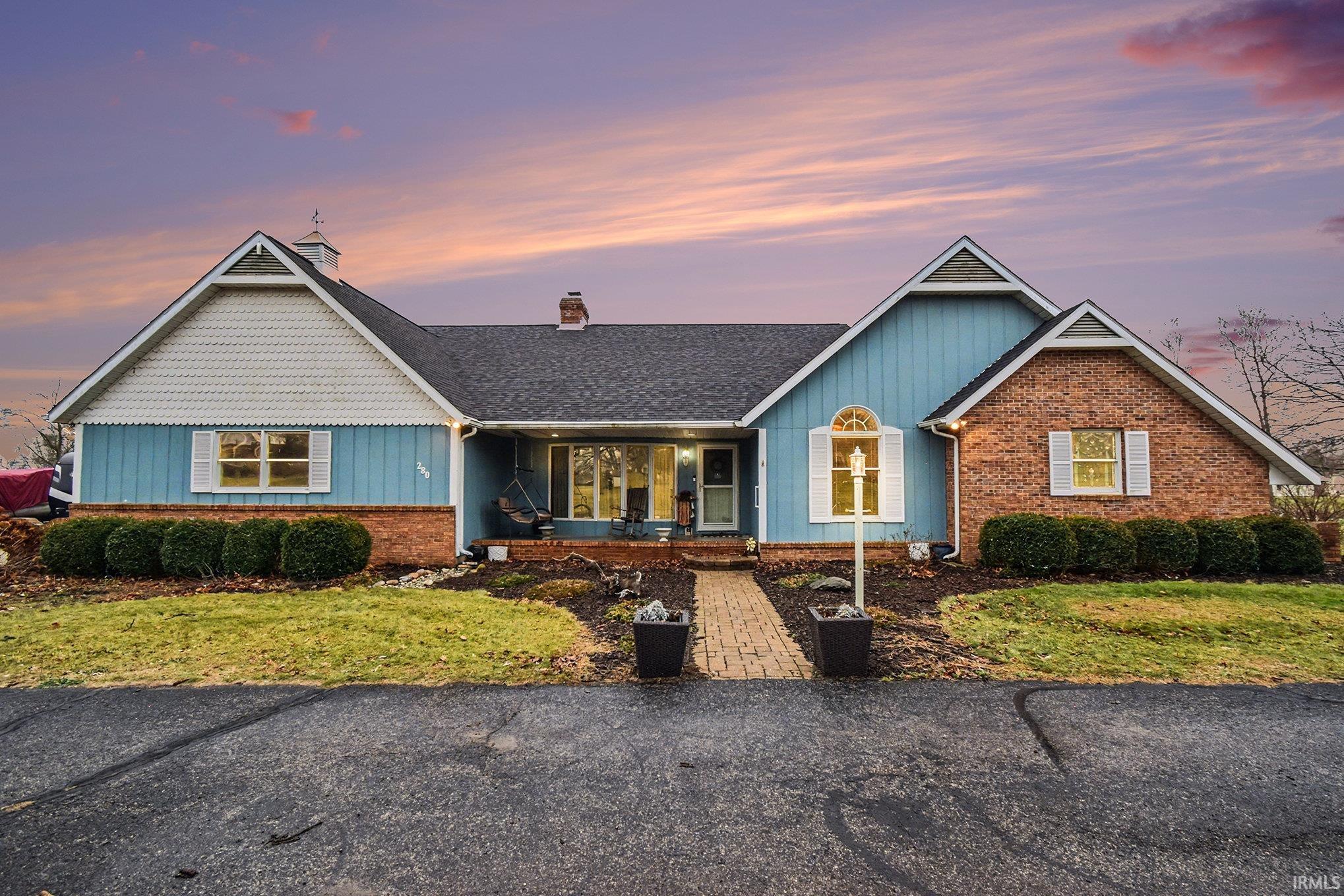 Single story home featuring a porch, a chimney, board and batten siding, and a lawn