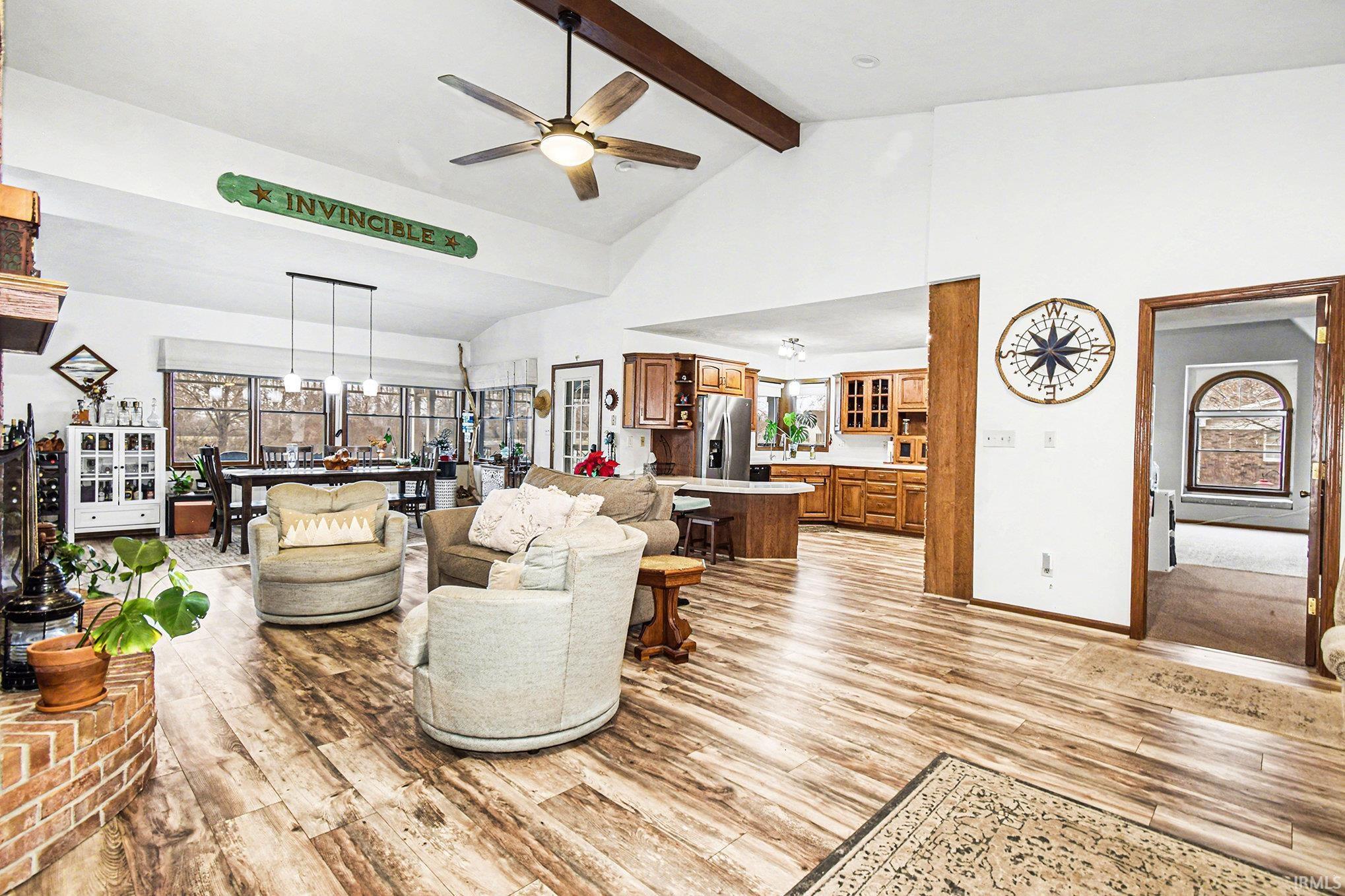 Living area with high vaulted ceiling, beam ceiling, light wood-type flooring, and a ceiling fan
