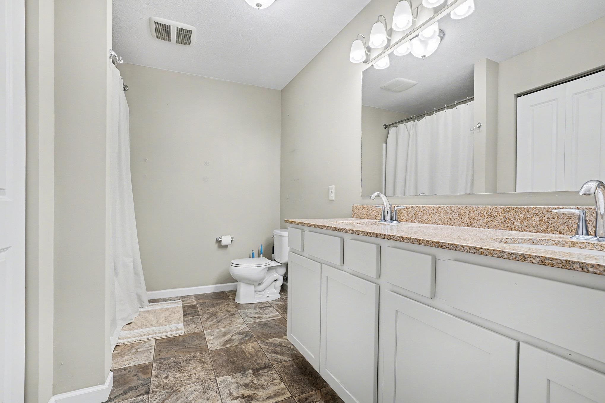 Full bath featuring double granite vanity, walk-in shower & linen closet