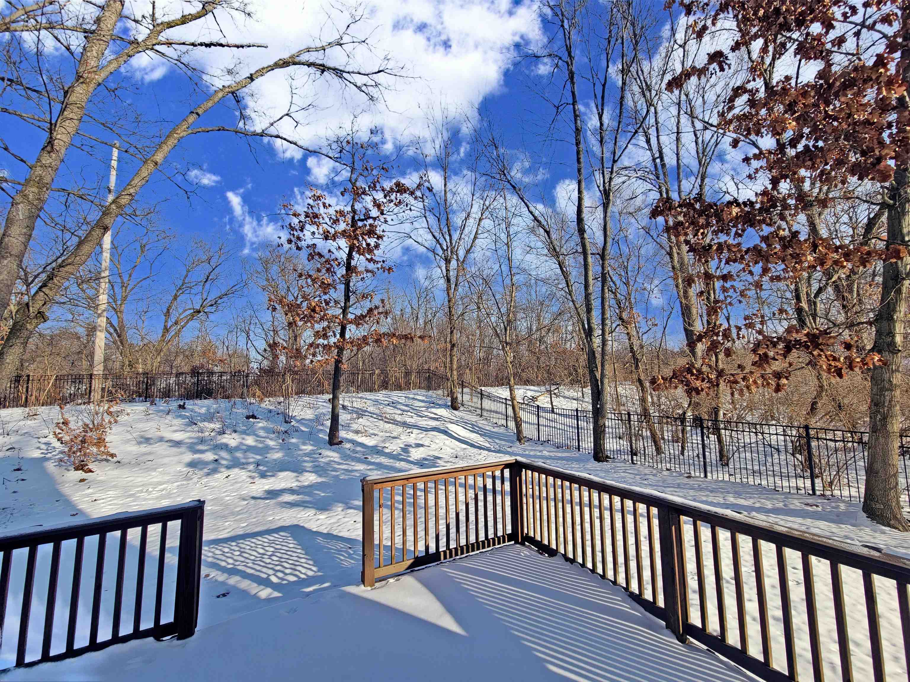 Yard layered in snow with a wooden deck stained in Summer 2025