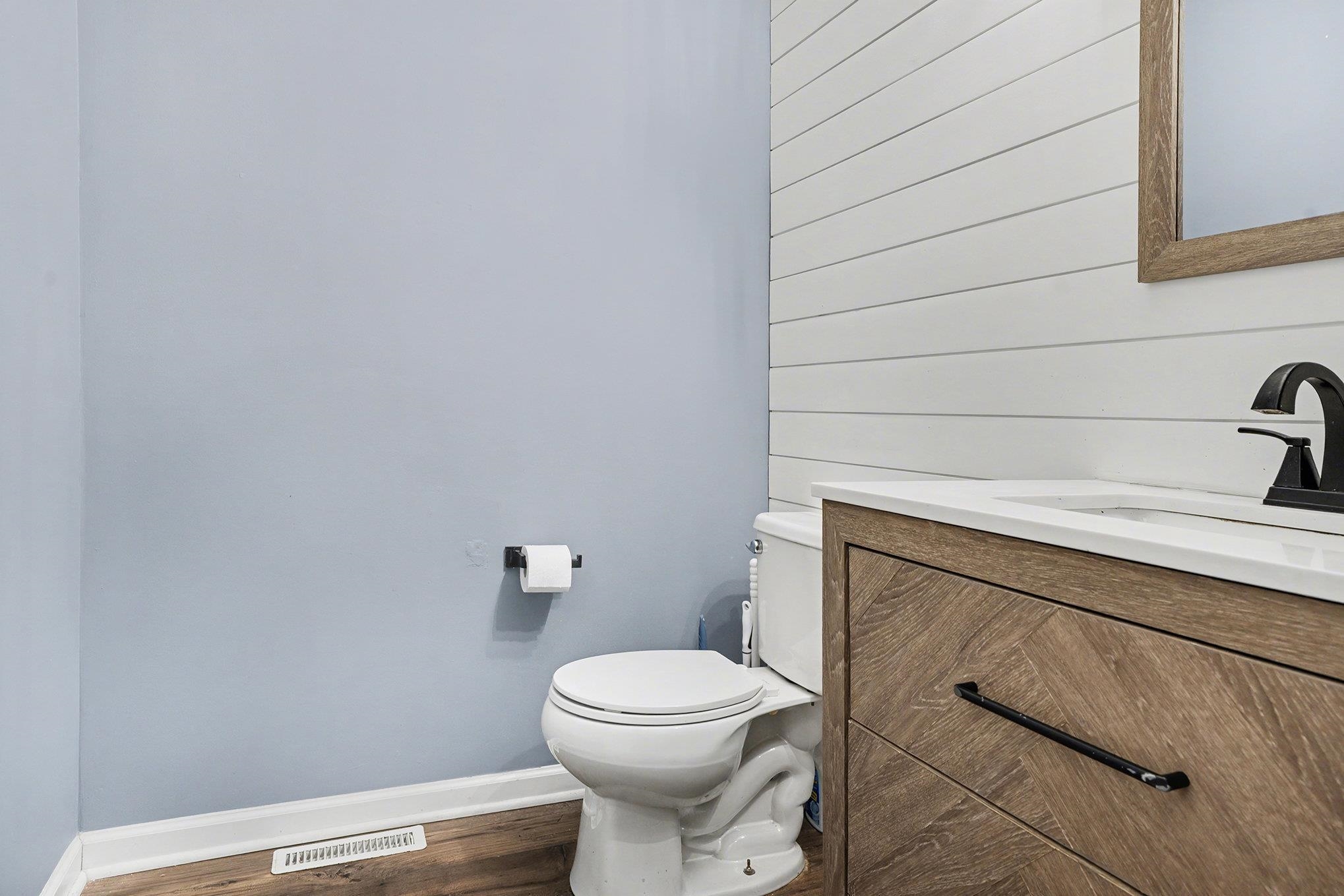 Bathroom featuring wooden walls, vanity, and dark wood-style floors on main floor