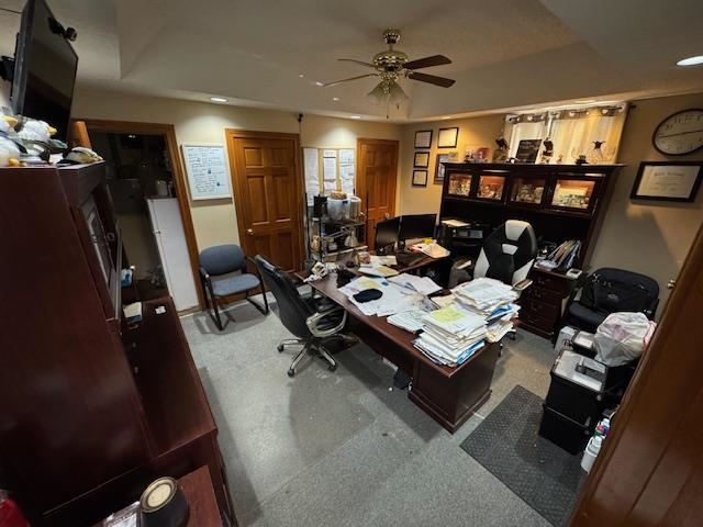 Home office featuring ceiling fan, a raised ceiling, carpet flooring, and recessed lighting