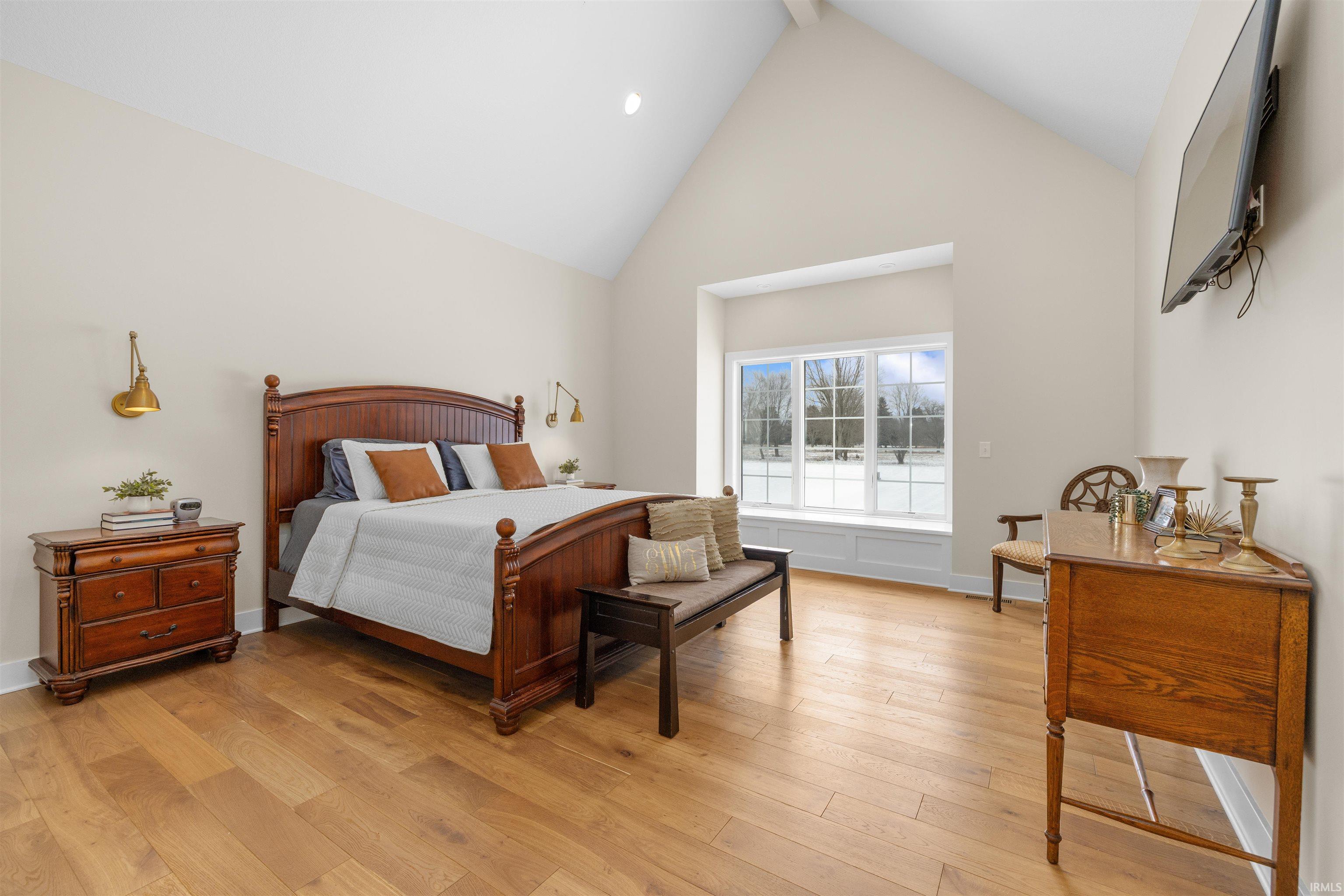 Bedroom with high vaulted ceiling, light wood-style floors, and beam ceiling