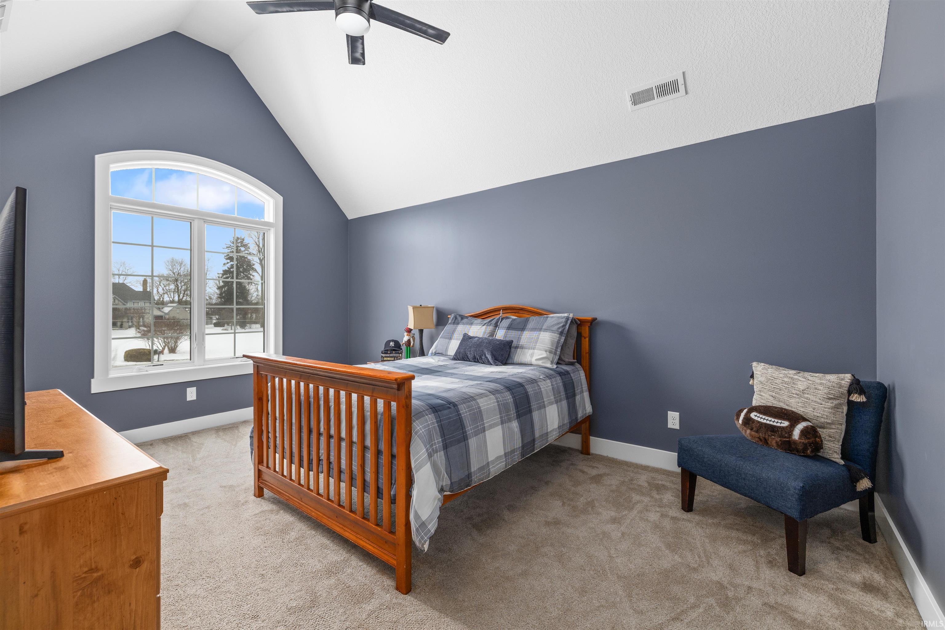 Bedroom featuring light colored carpet, vaulted ceiling, and ceiling fan