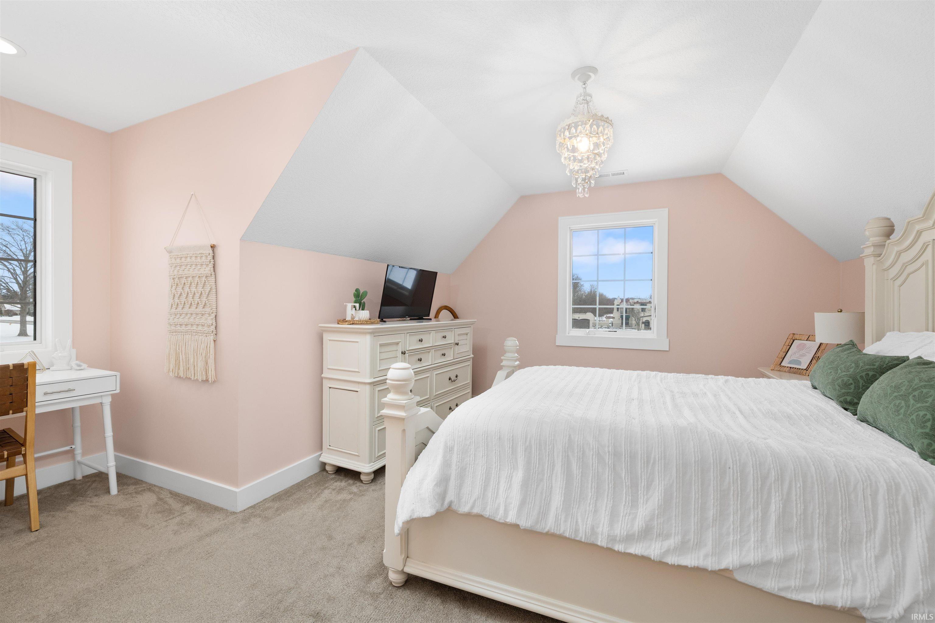Bedroom with carpet flooring, lofted ceiling, and a chandelier
