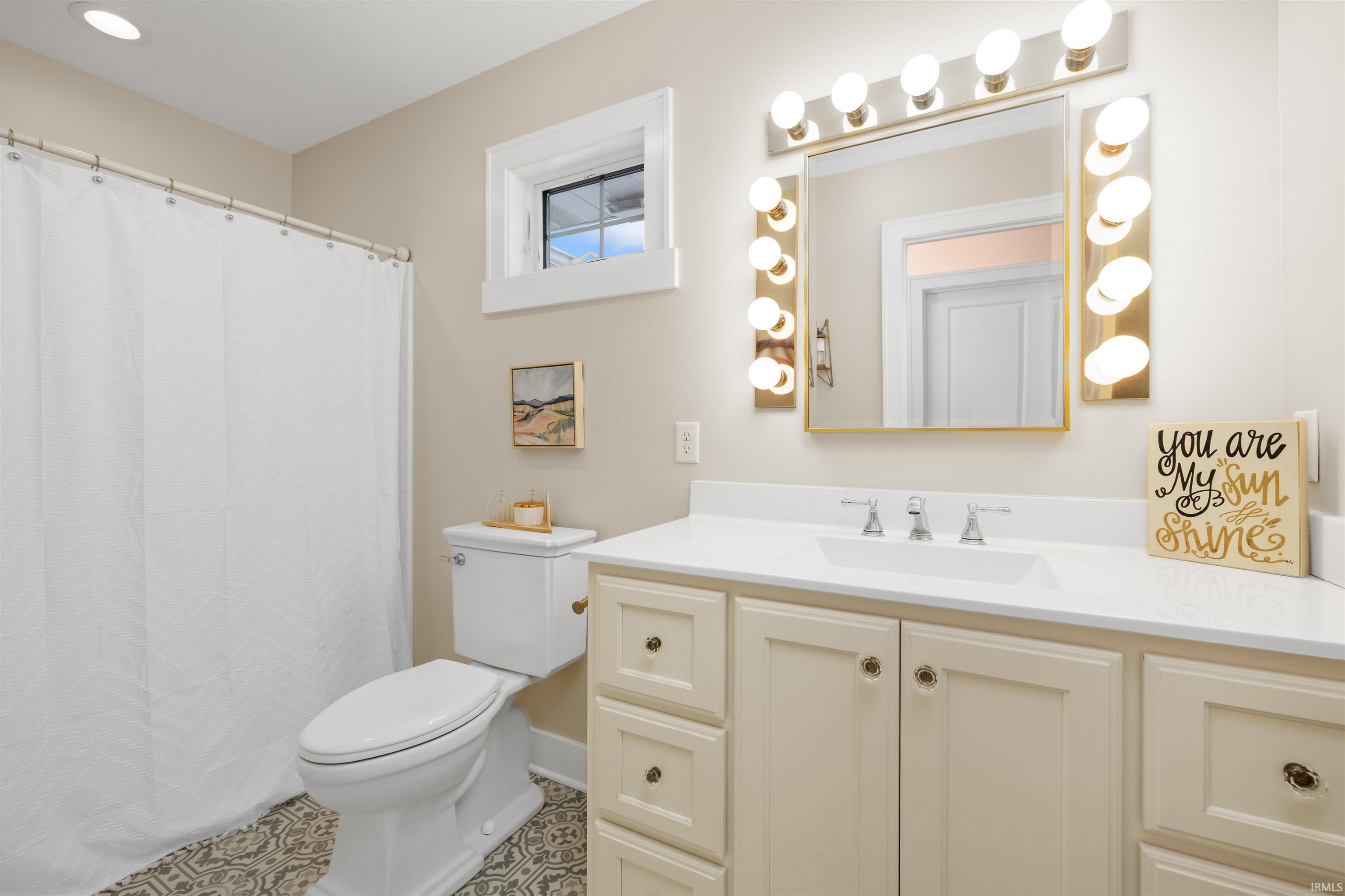 Bathroom with vanity, a shower with shower curtain, and tile patterned floors