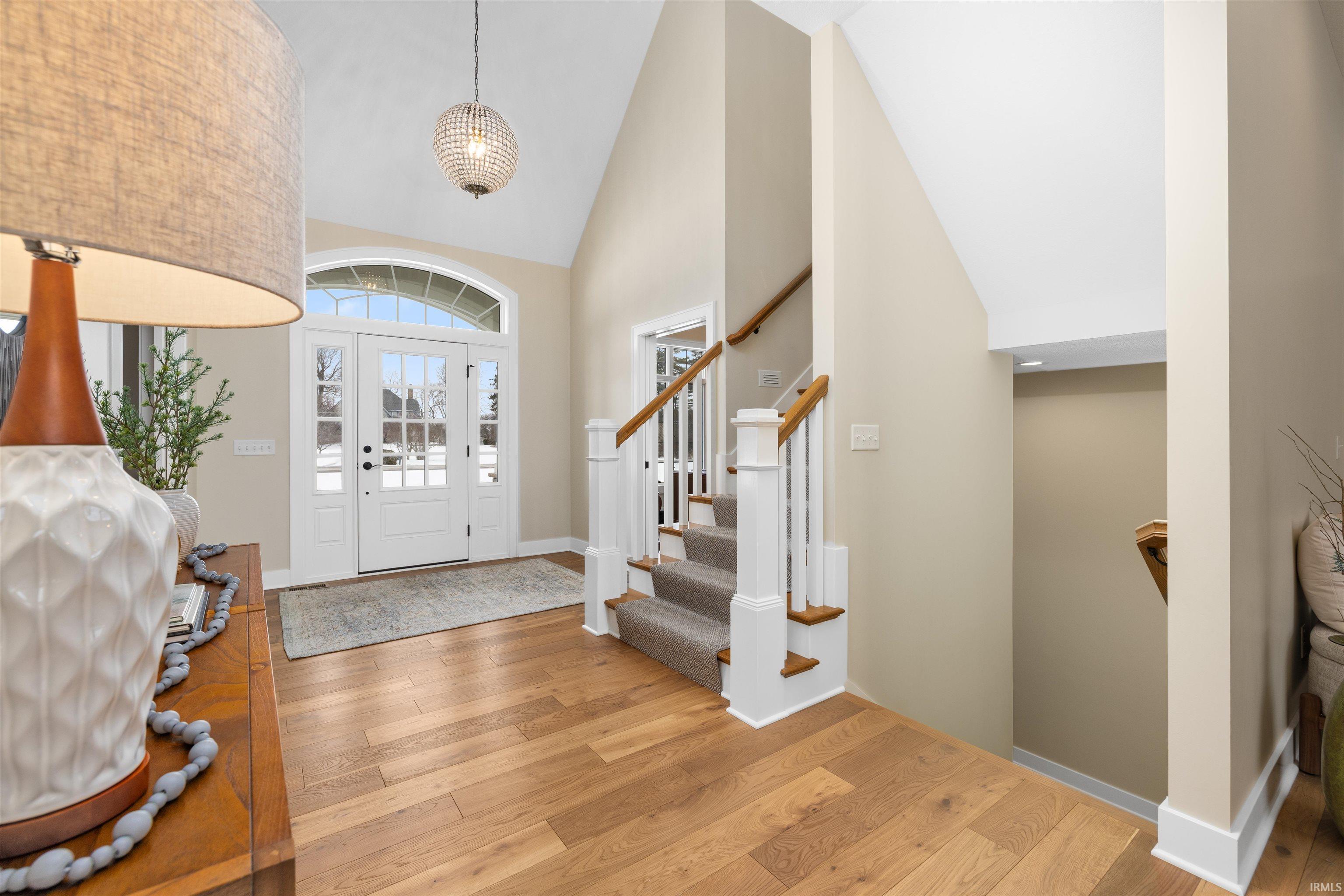 Foyer featuring high vaulted ceiling, stairway, and light wood-type flooring