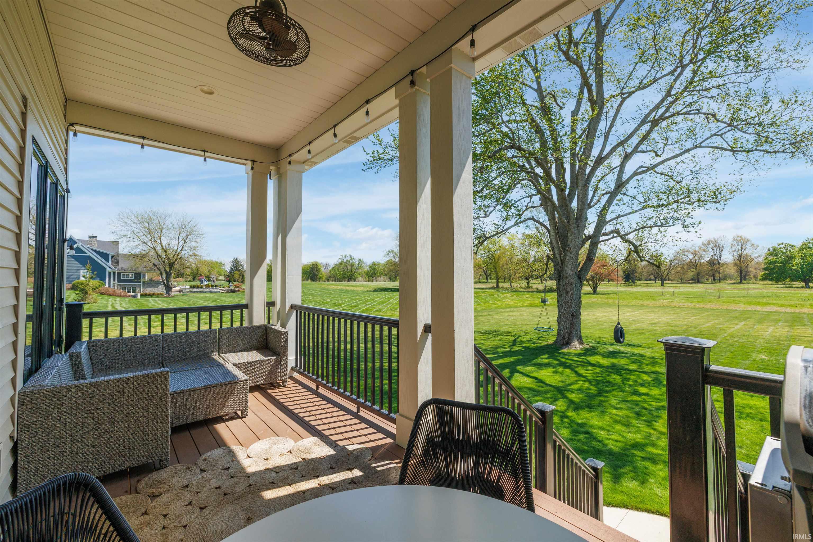 Expansive covered porch featuring a composite deck surface, white support columns, and dark railing