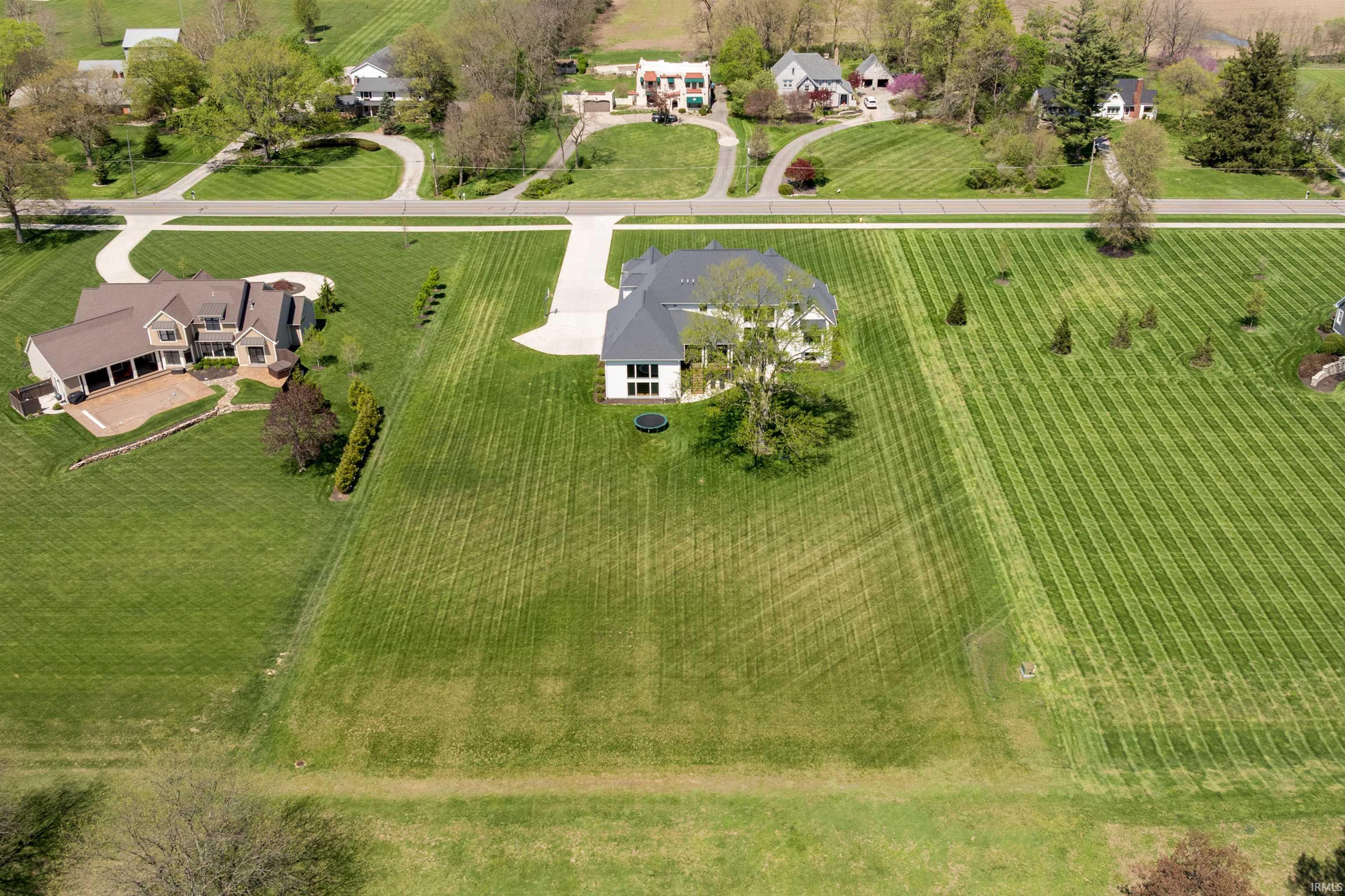 Expansive green property with a contemporary-style residence featuring a dark roof and light siding