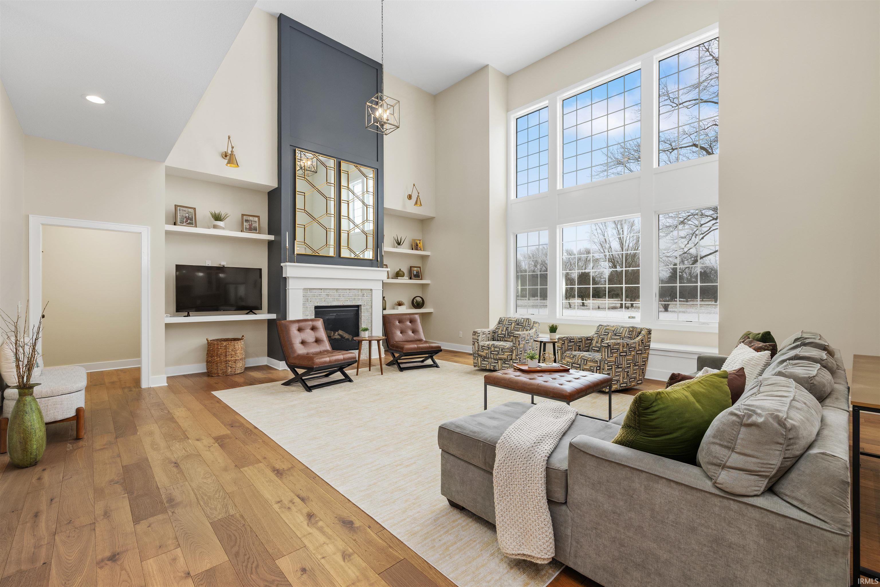 Living room with built in shelves, hardwood / wood-style floors, a high ceiling, and a fireplace