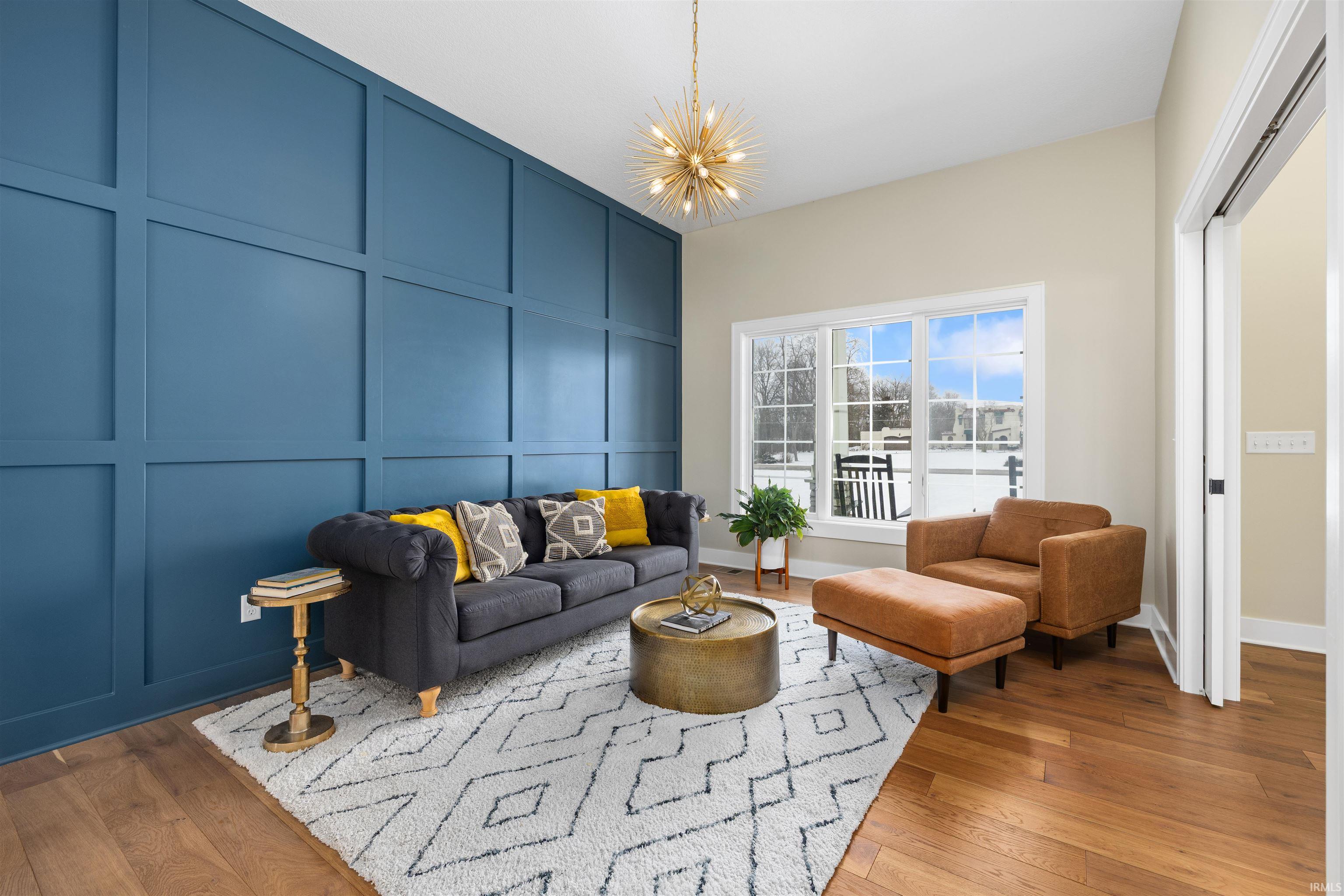 Living area featuring a decorative wall, hardwood / wood-style floors, a chandelier, and an accent wall