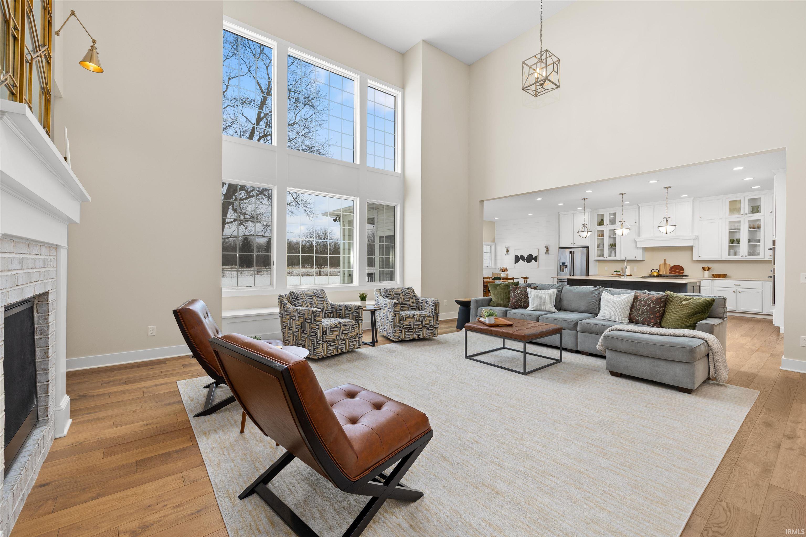 Living area with a fireplace, light wood finished floors, and a towering ceiling