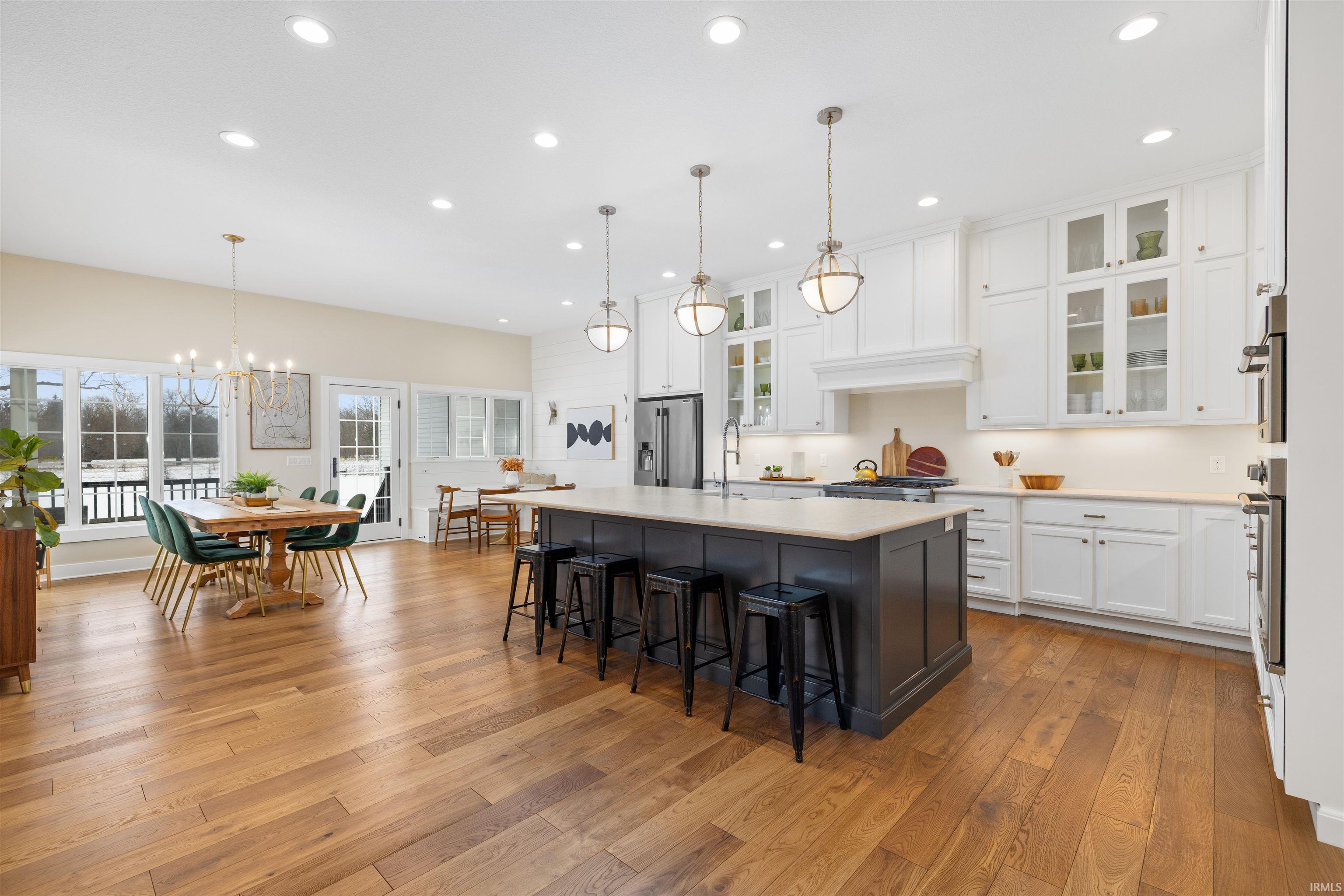 Kitchen featuring hanging light fixtures, white cabinetry, a center island with sink, a breakfast bar, and light wood-style flooring