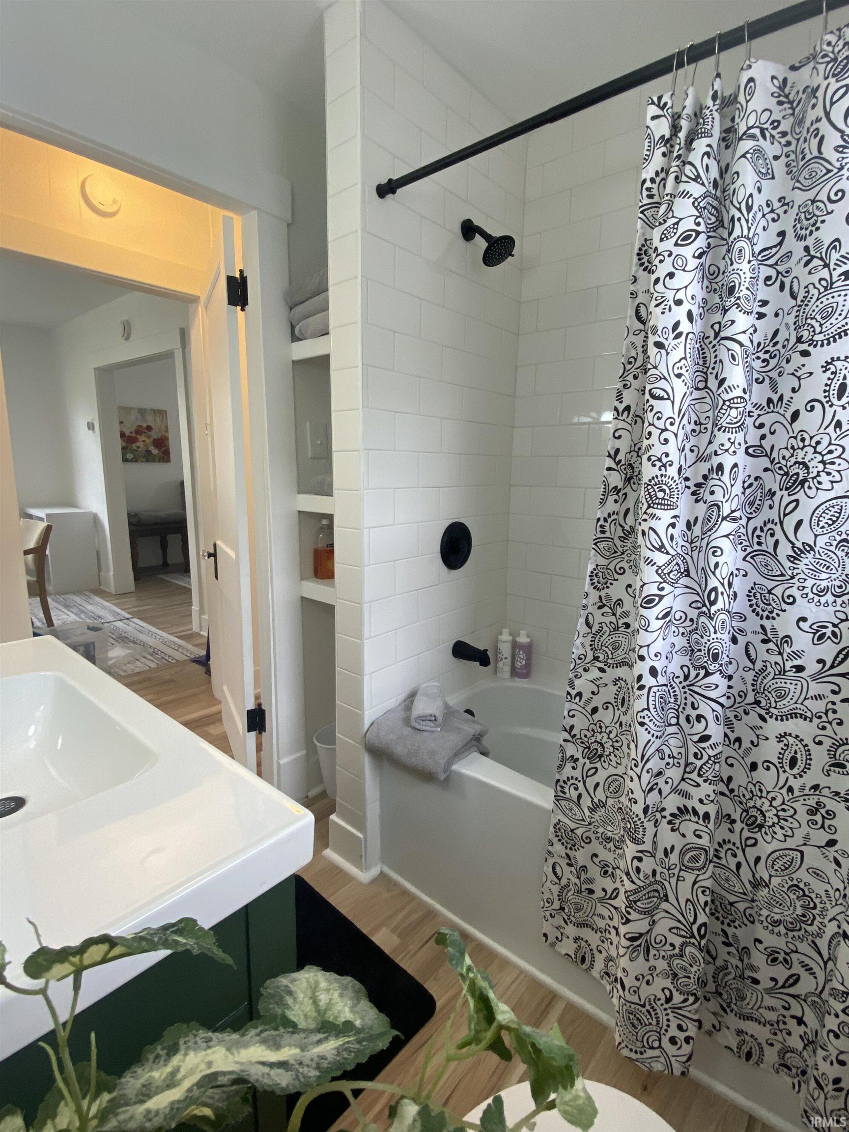 Bathroom featuring light wood finished floors, vanity, and shower / bath combo with shower curtain