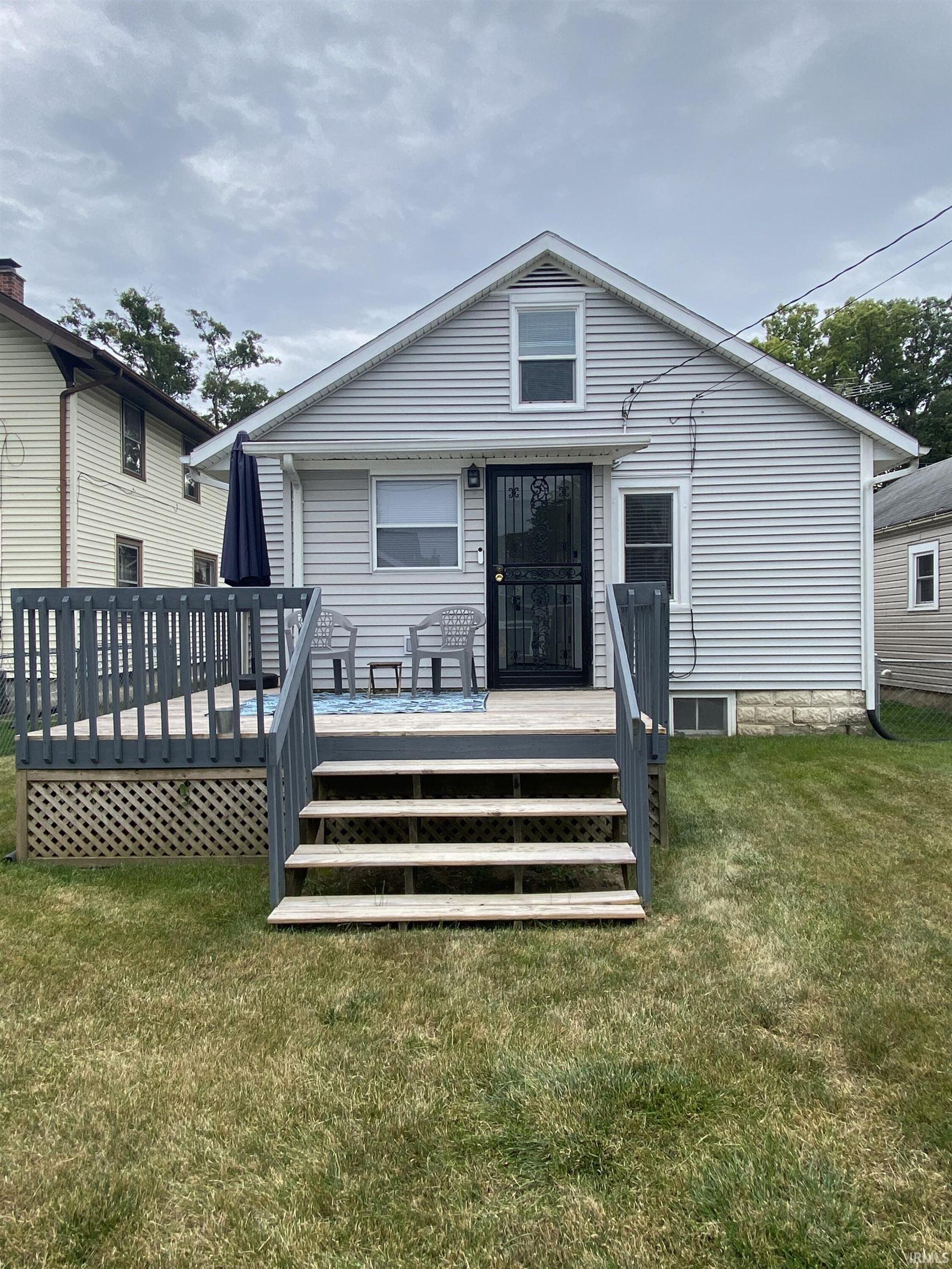 Back of property featuring a deck and a lawn