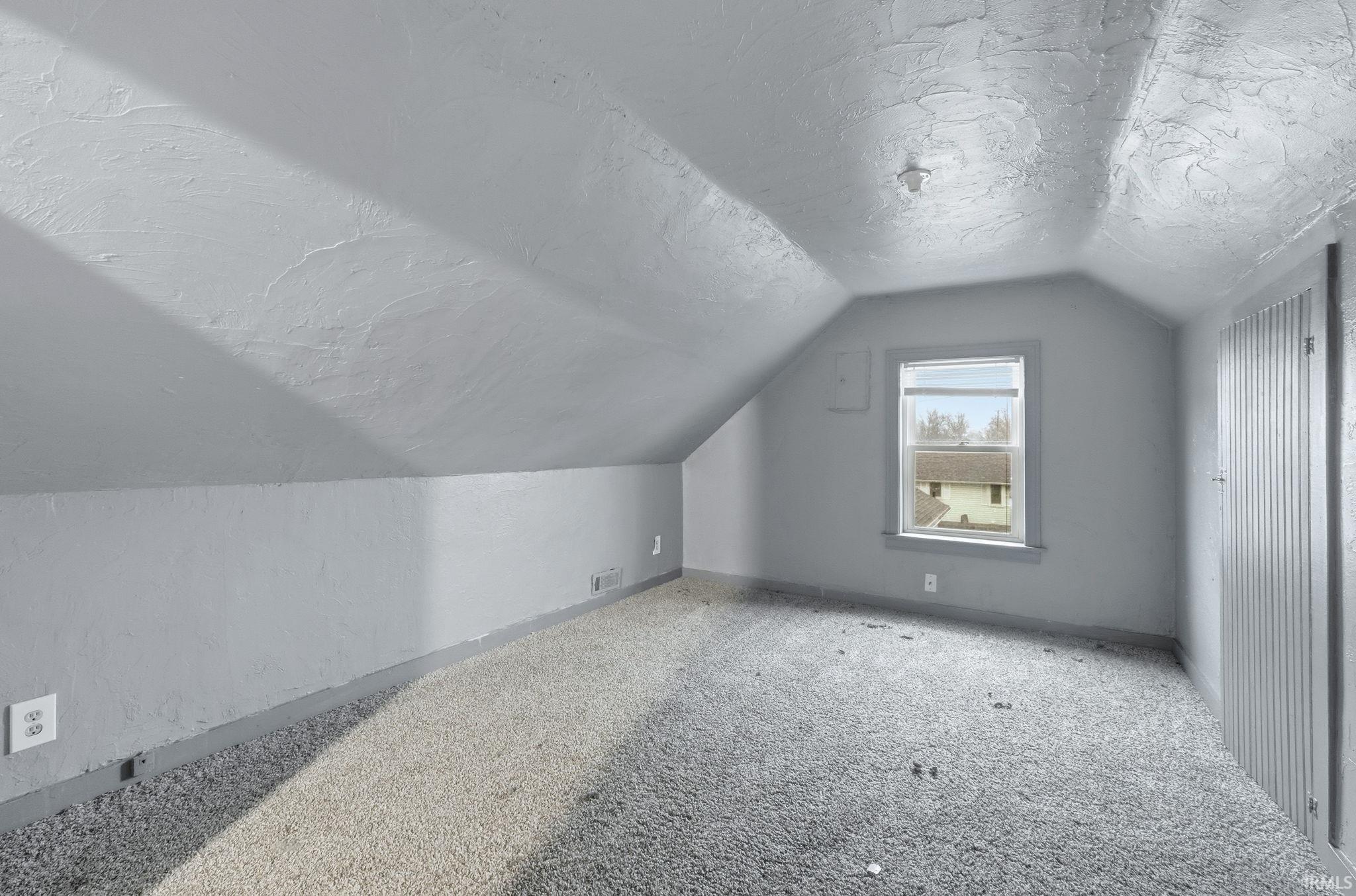 Bonus room with a textured ceiling, lofted ceiling, carpet floors, and a textured wall