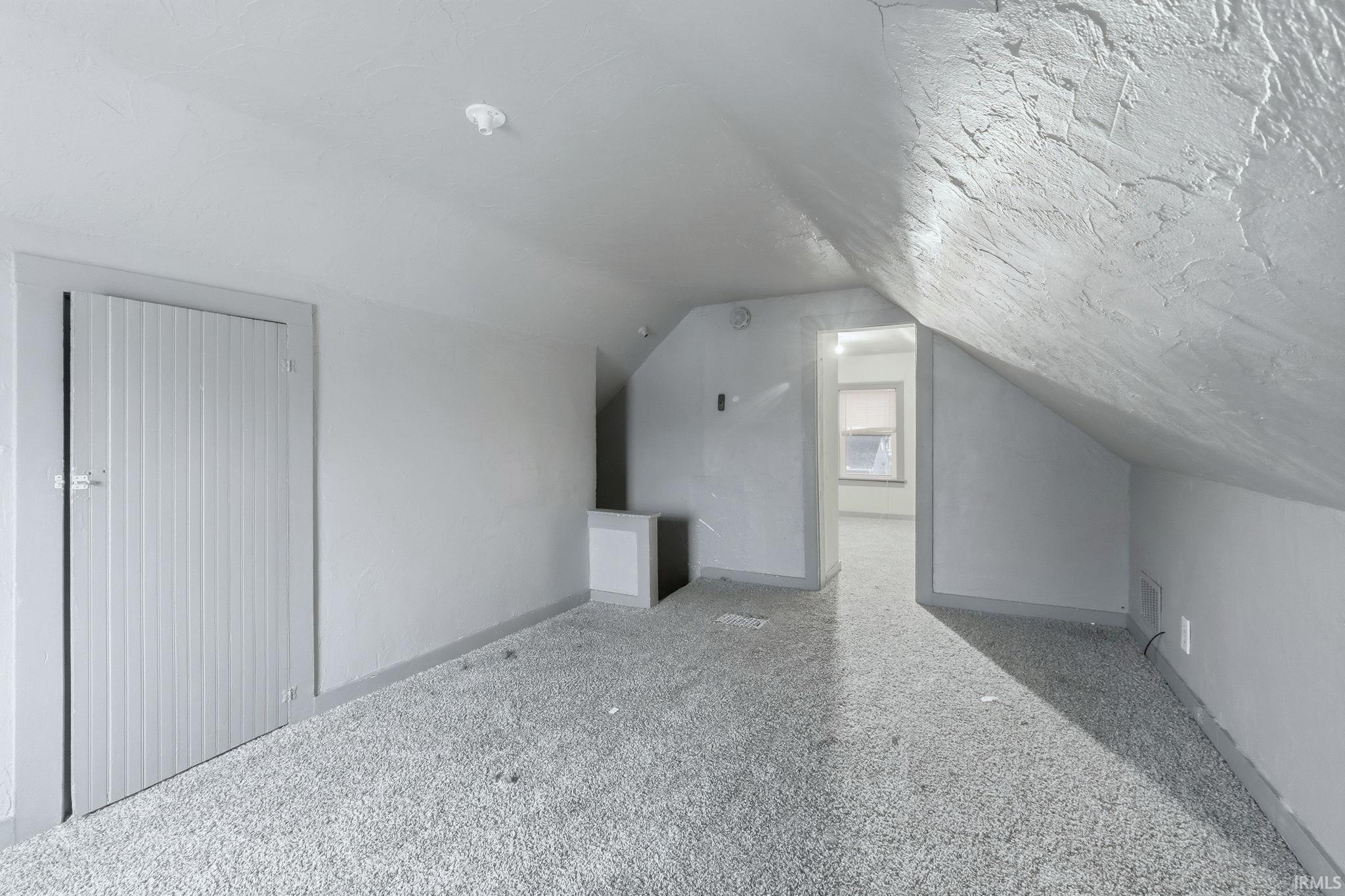 Additional living space featuring vaulted ceiling and baseboards