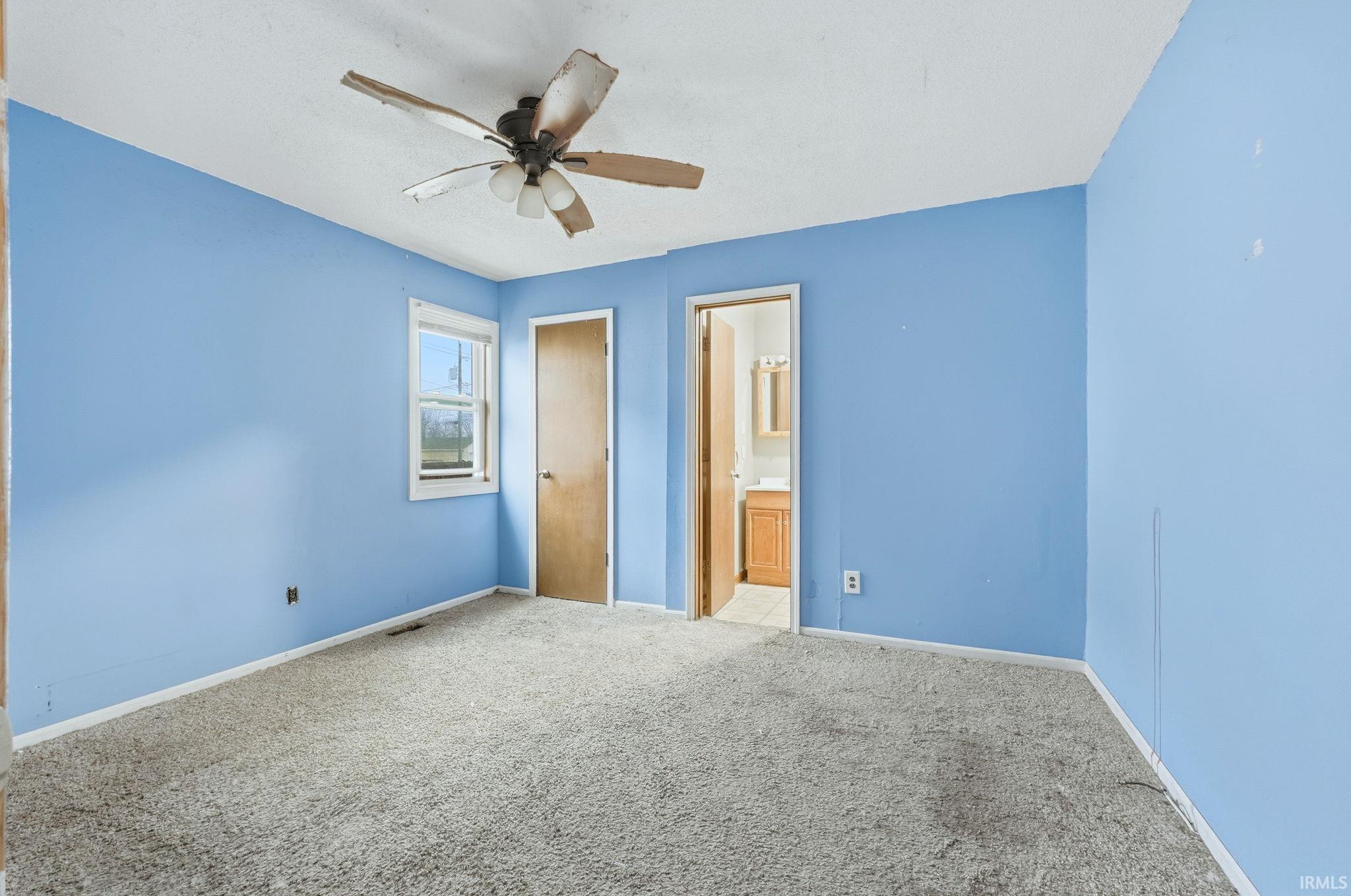 Unfurnished bedroom featuring carpet flooring, a ceiling fan, and ensuite bathroom