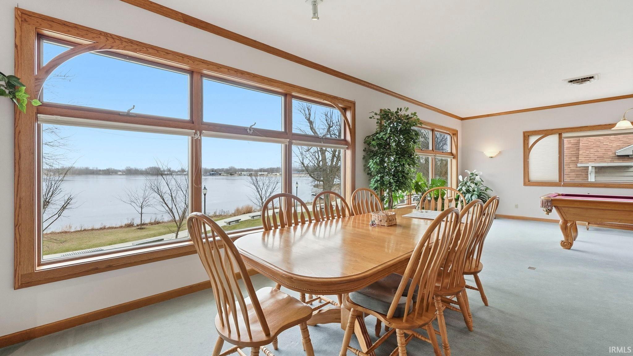 Carpeted dining space featuring a water view, pool table, and crown molding