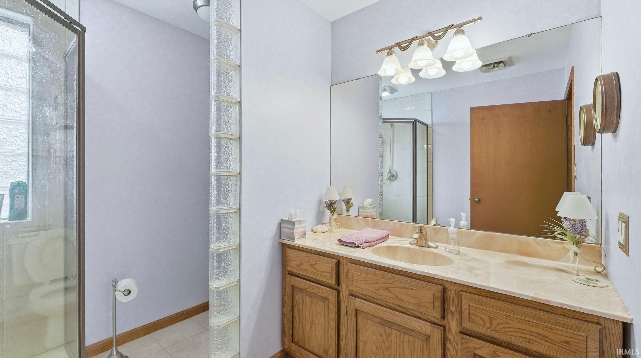 Bathroom with a shower stall, vanity, and light tile patterned flooring