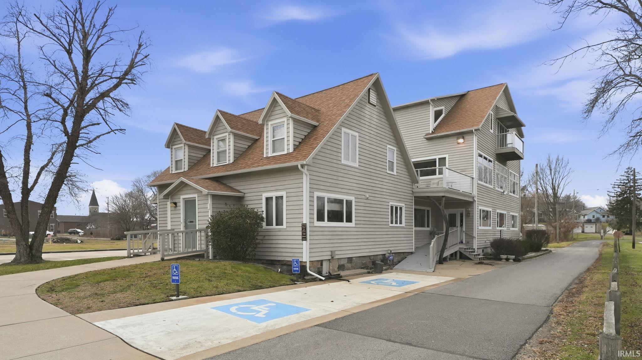 View of side of property featuring a shingled roof, a lawn, and a residential view