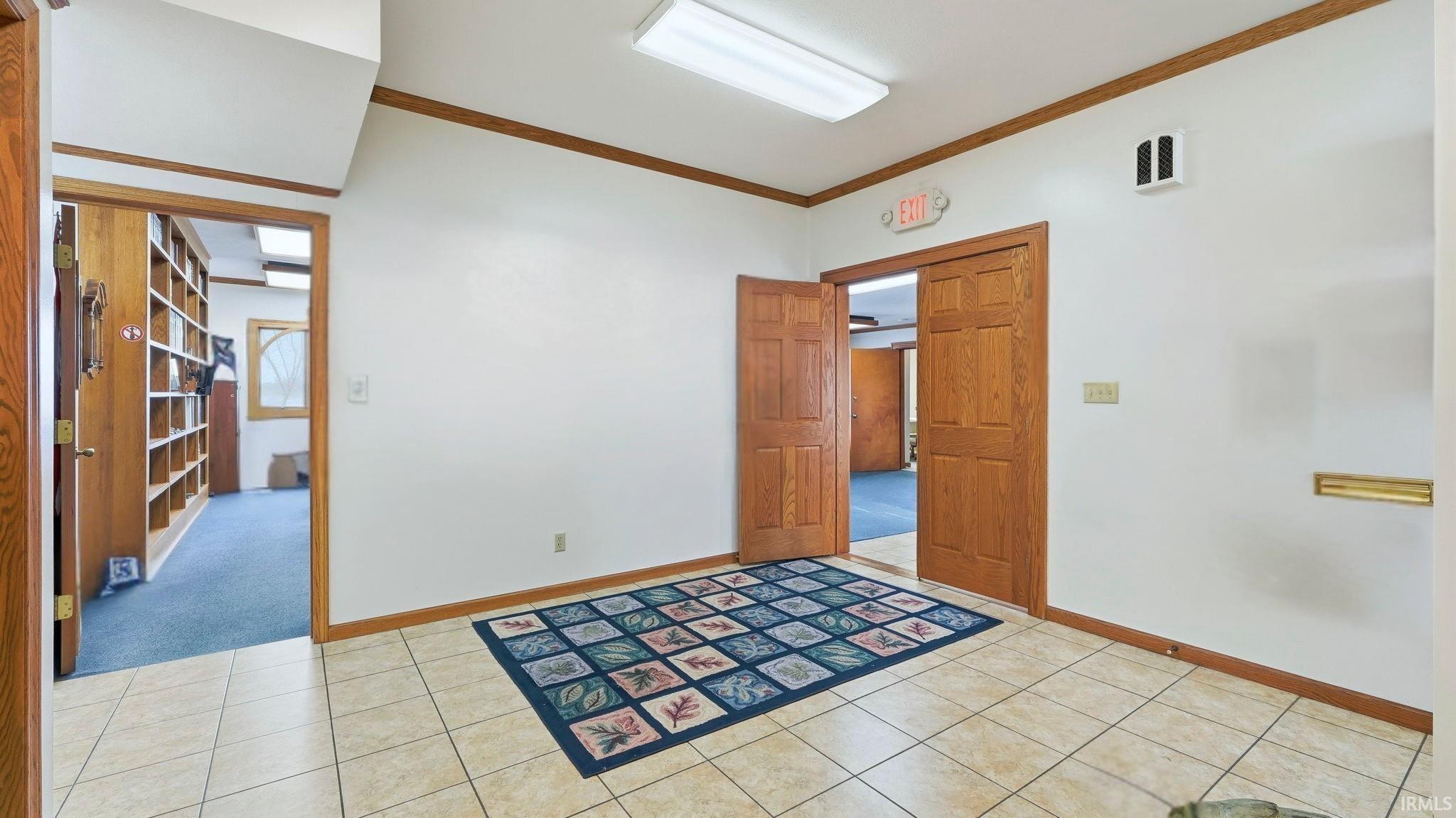 Empty room featuring ornamental molding and light tile patterned floors