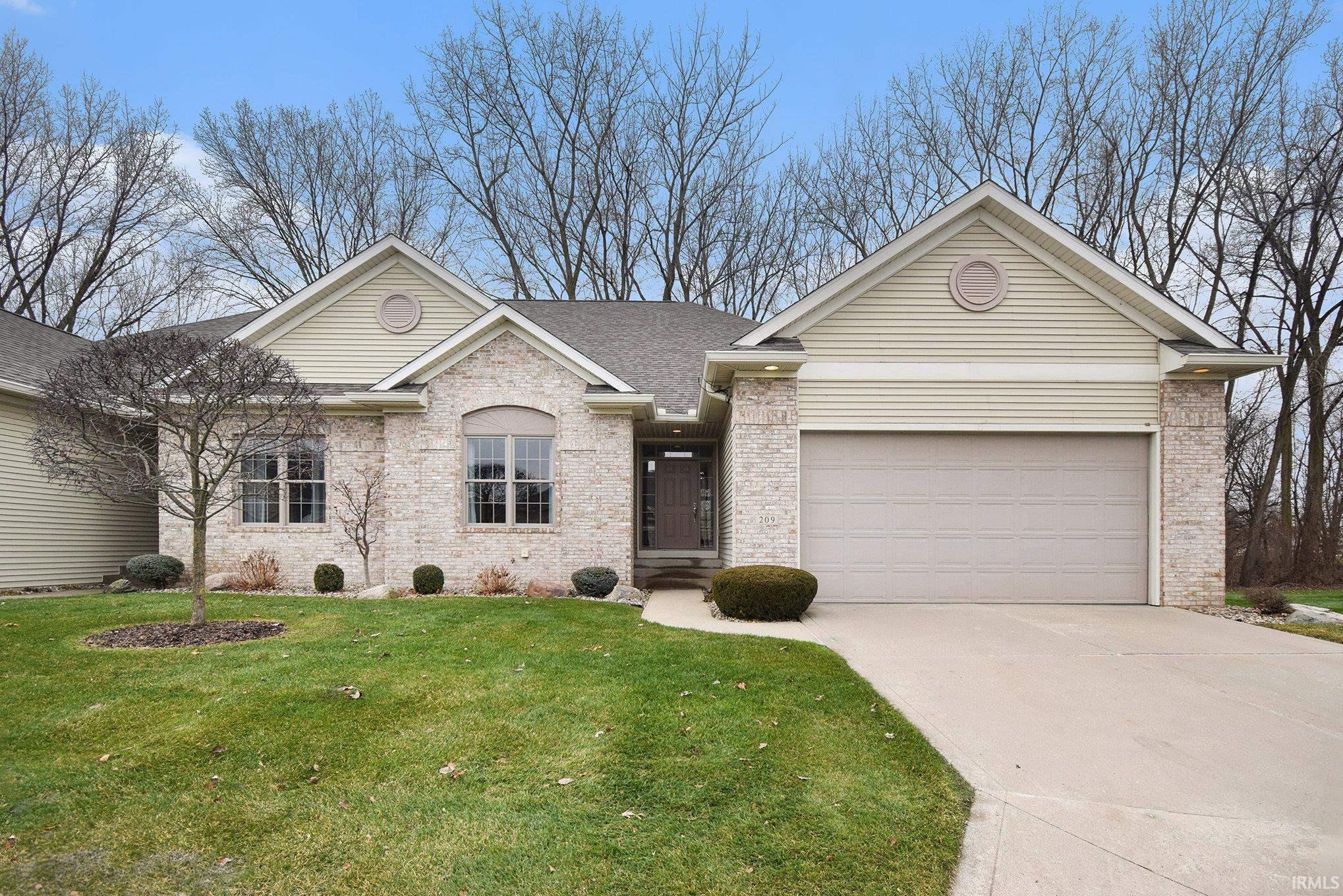 Ranch-style house featuring brick siding, a front yard, driveway, a shingled roof, and an attached garage