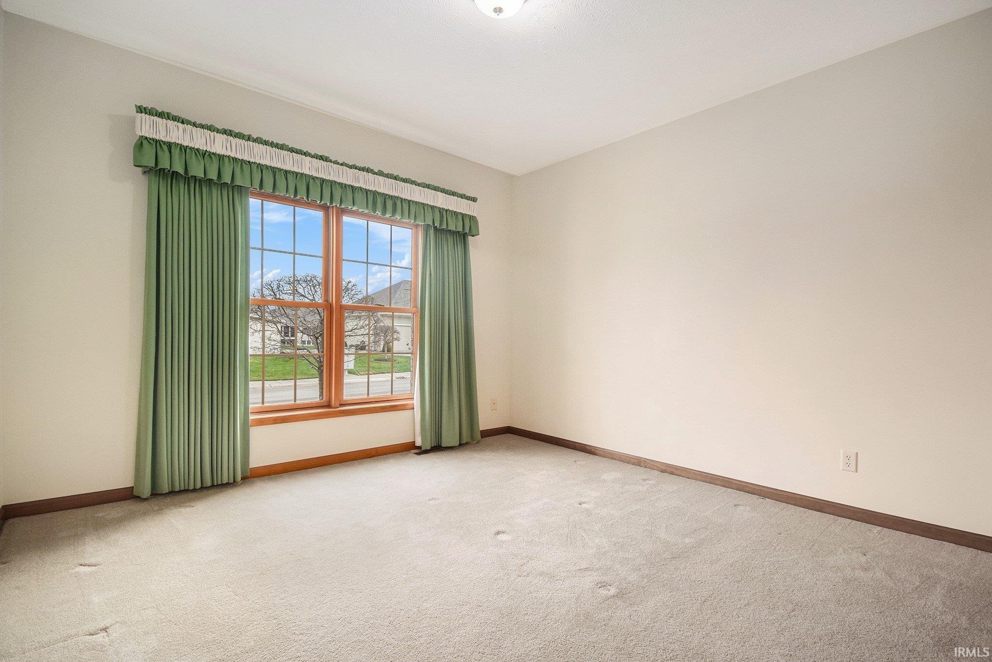 Unfurnished room featuring light carpet and baseboards