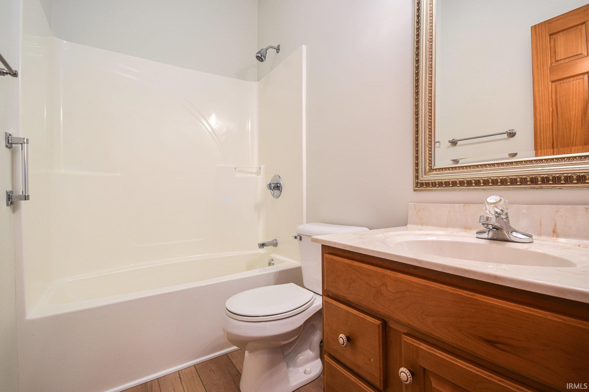 Bathroom featuring washtub / shower combination, vanity, and light wood-style flooring