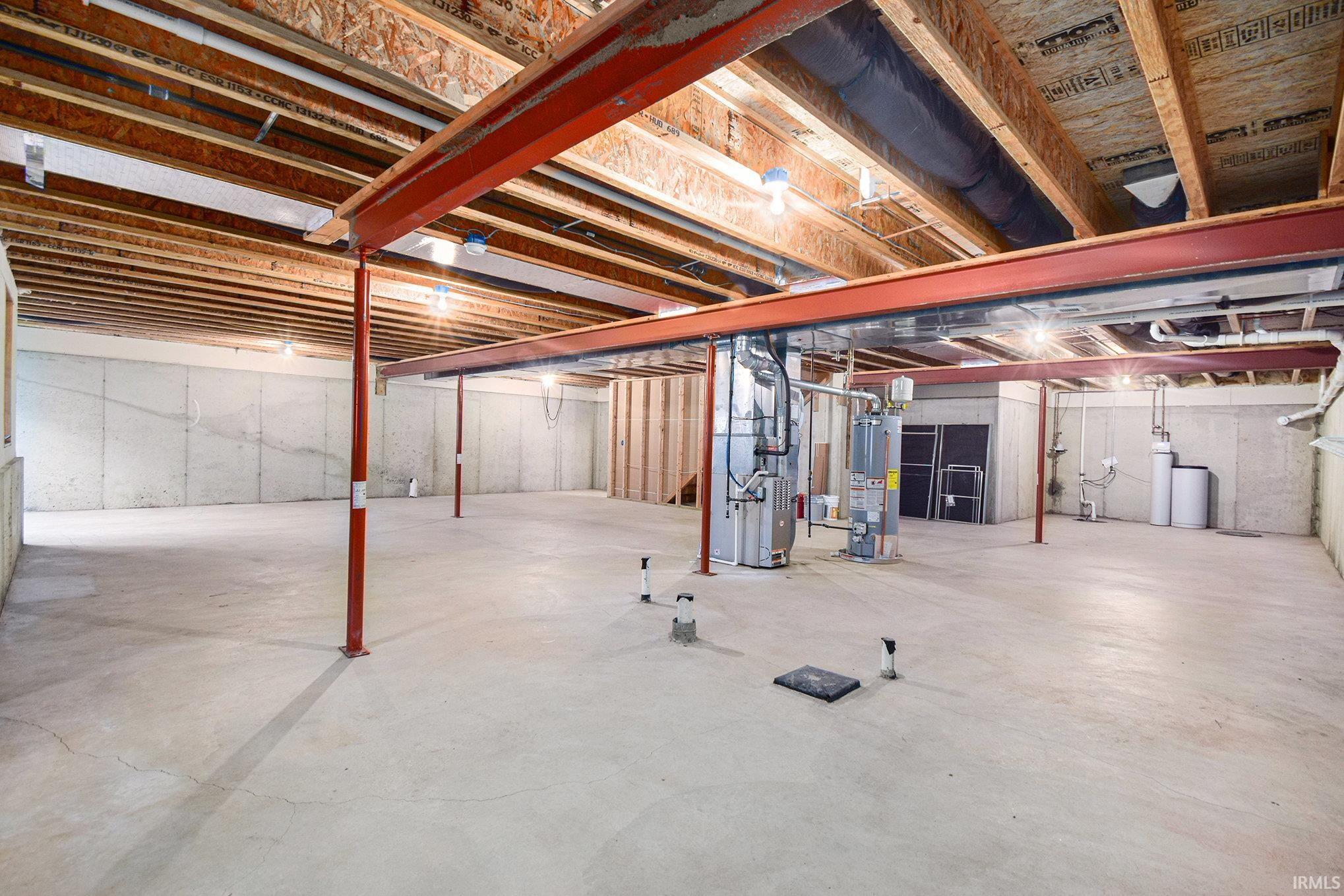 Unfinished below grade area featuring heating unit, gas water heater, and a water softener system
