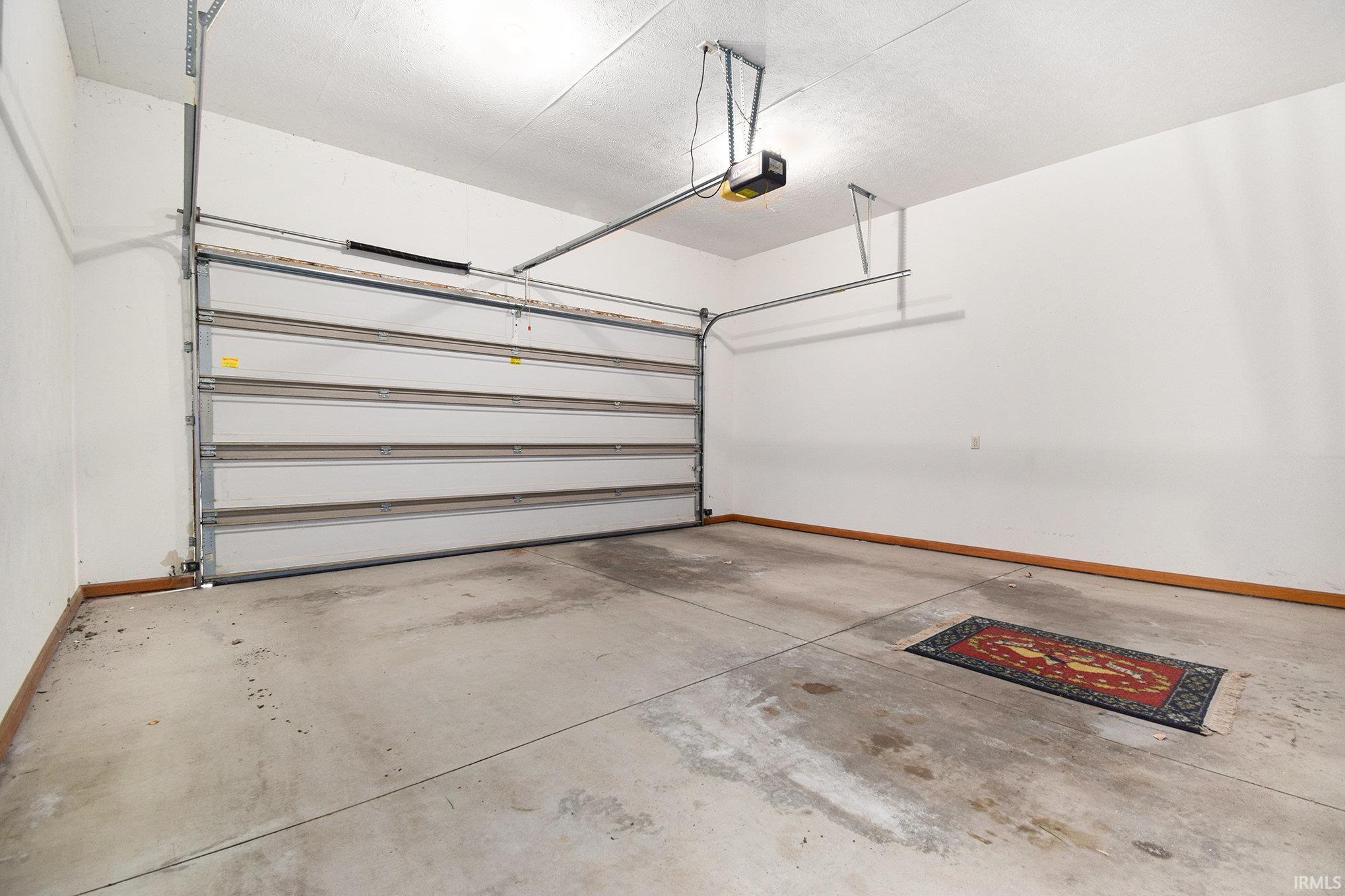 Garage featuring baseboards and a garage door opener