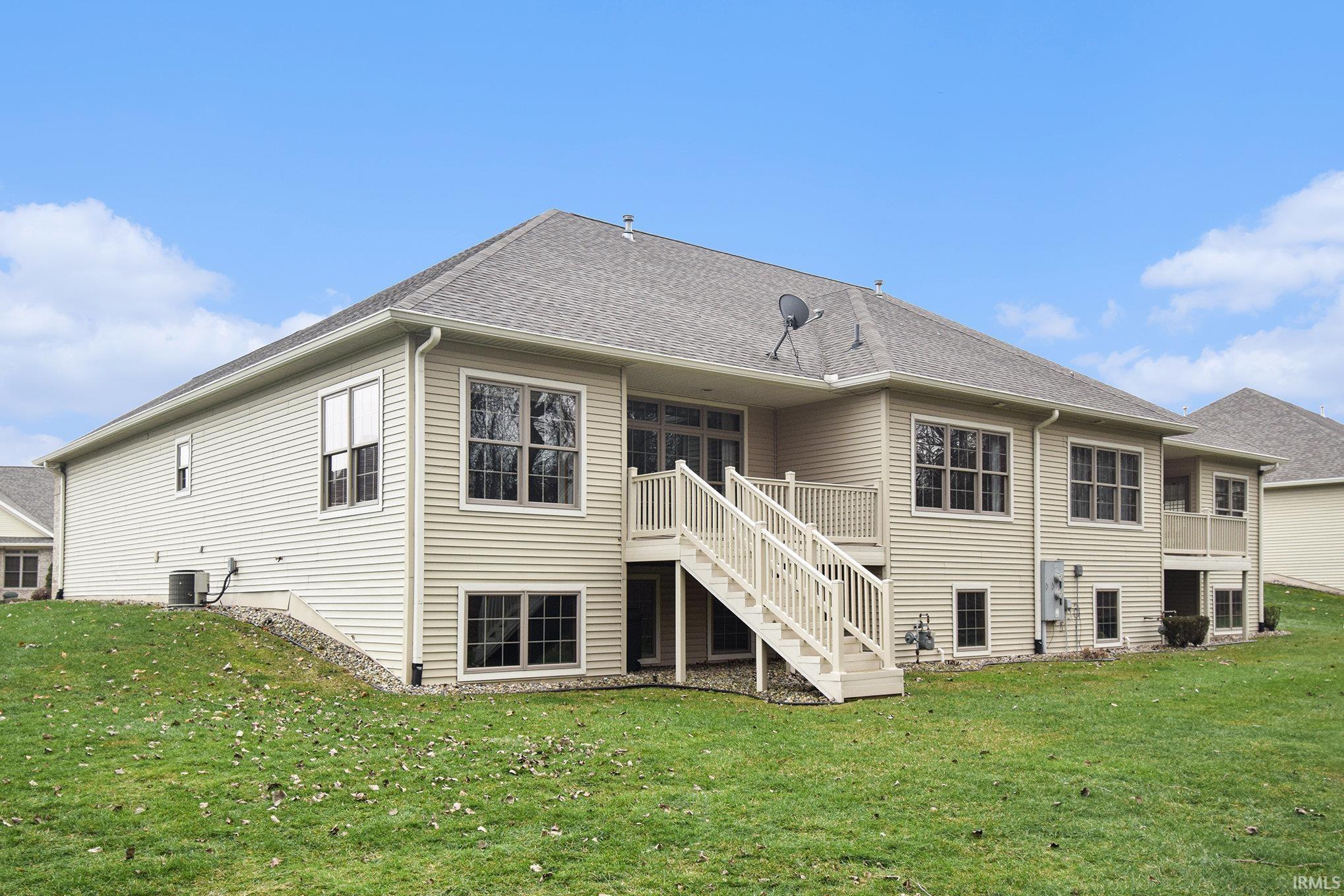 Rear view of house featuring stairs, a yard, and a shingled roof