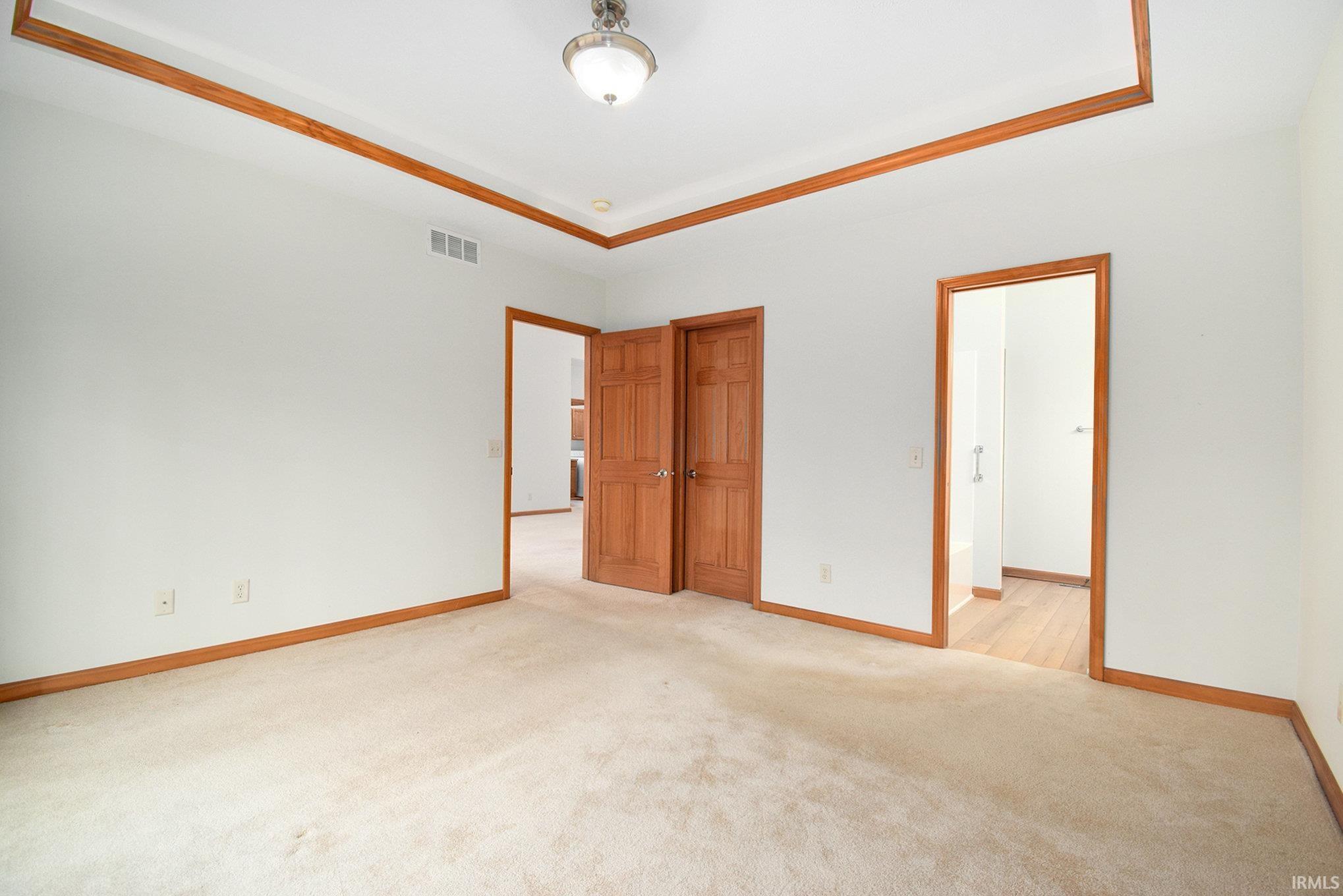 Unfurnished bedroom featuring light colored carpet and a raised ceiling