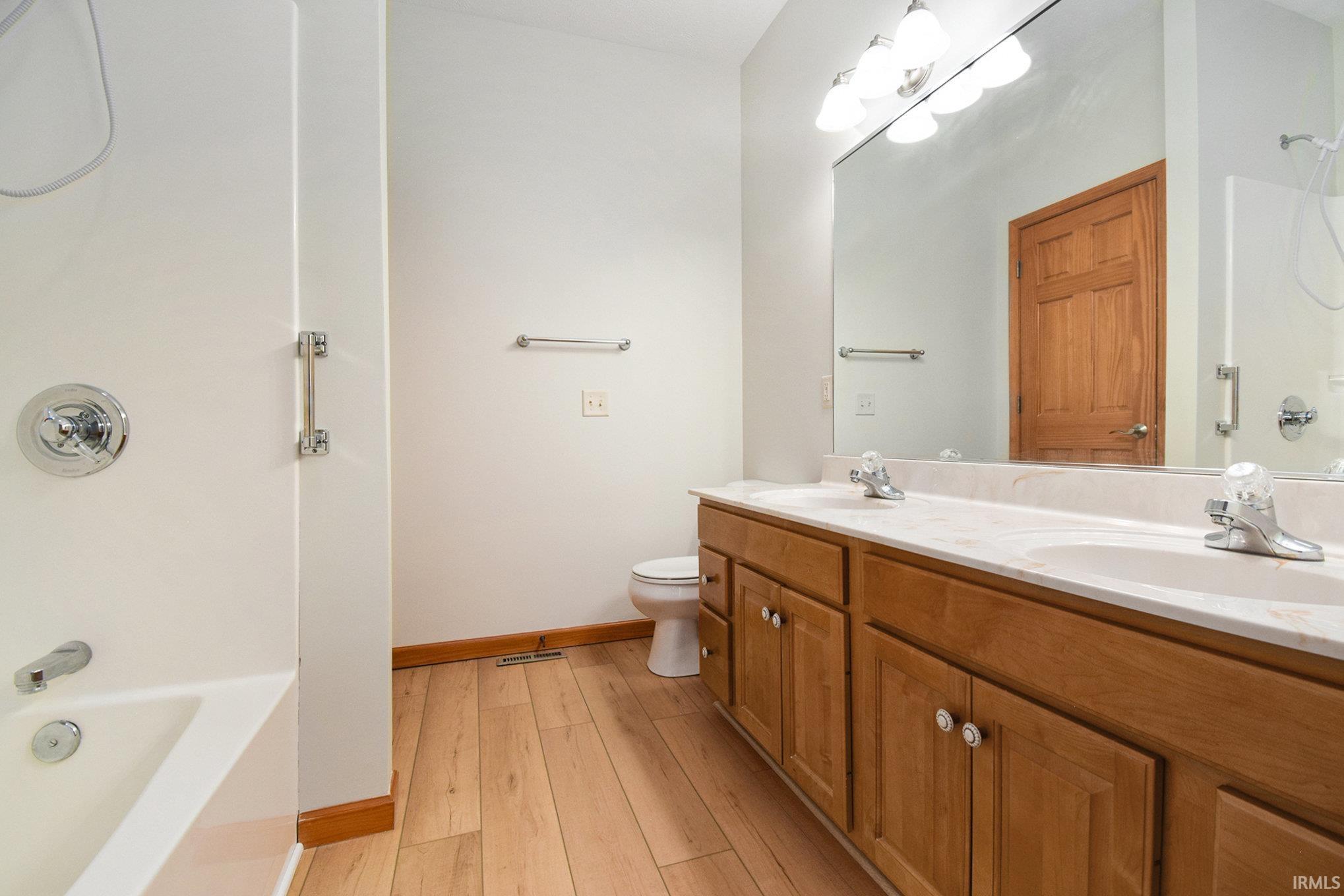 Bathroom featuring shower / tub combination, double vanity, and light wood-type flooring