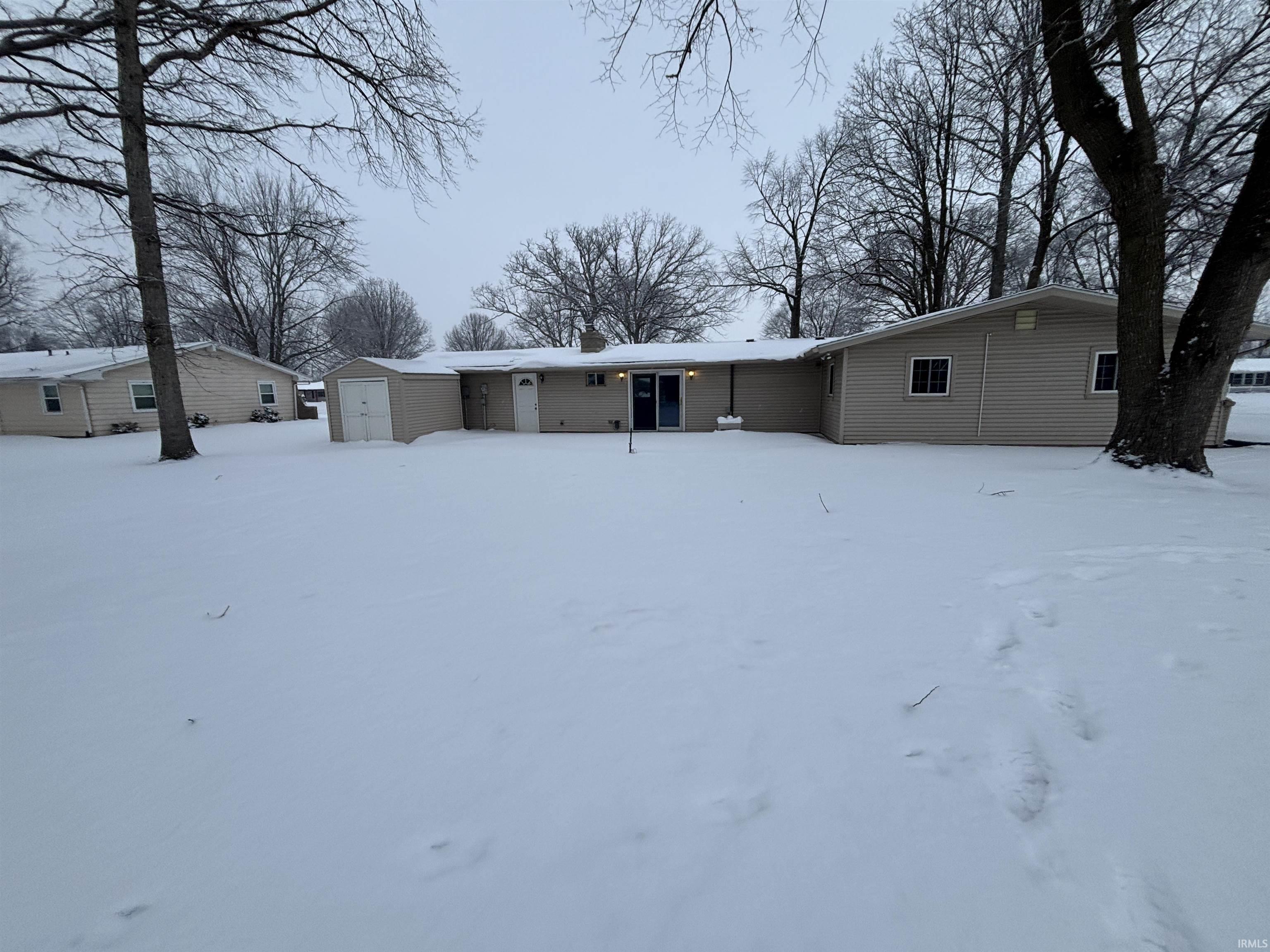 Snow covered house featuring a shed and a chimney