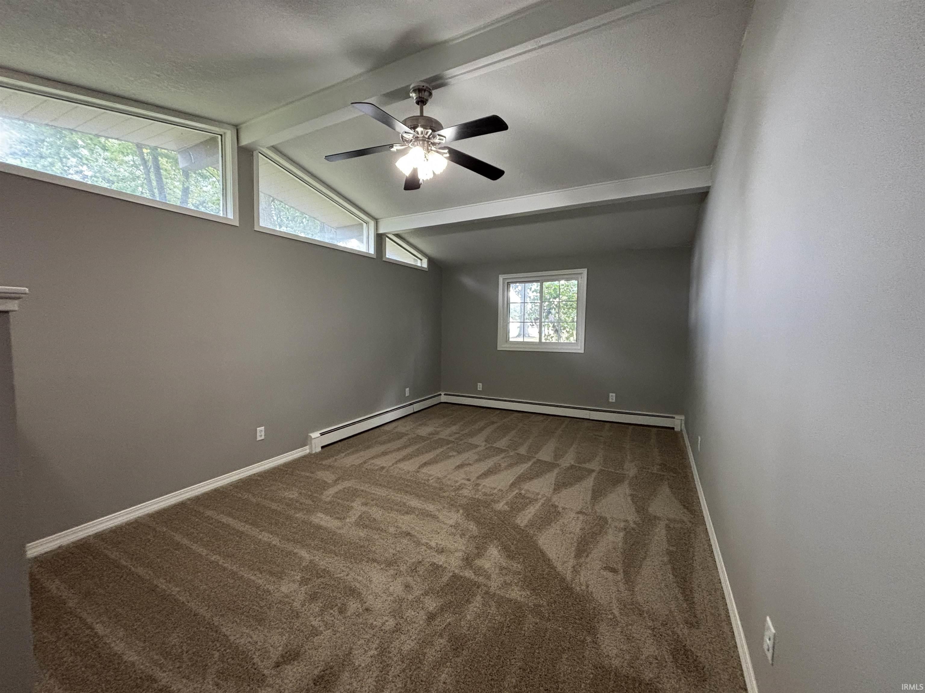 Spare room featuring light colored carpet, baseboard heating, and ceiling fan