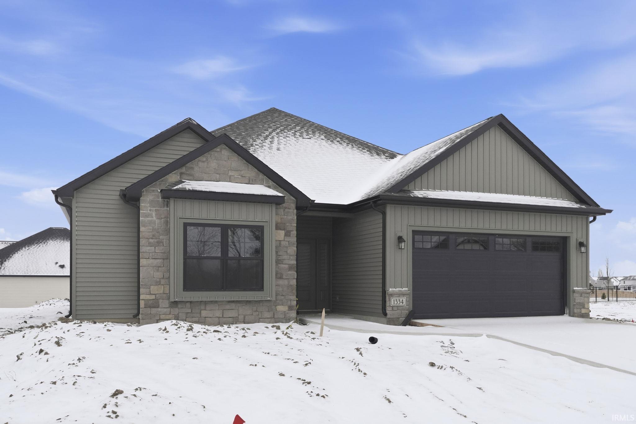 View of front of house with stone siding, an attached garage, and board and batten siding
