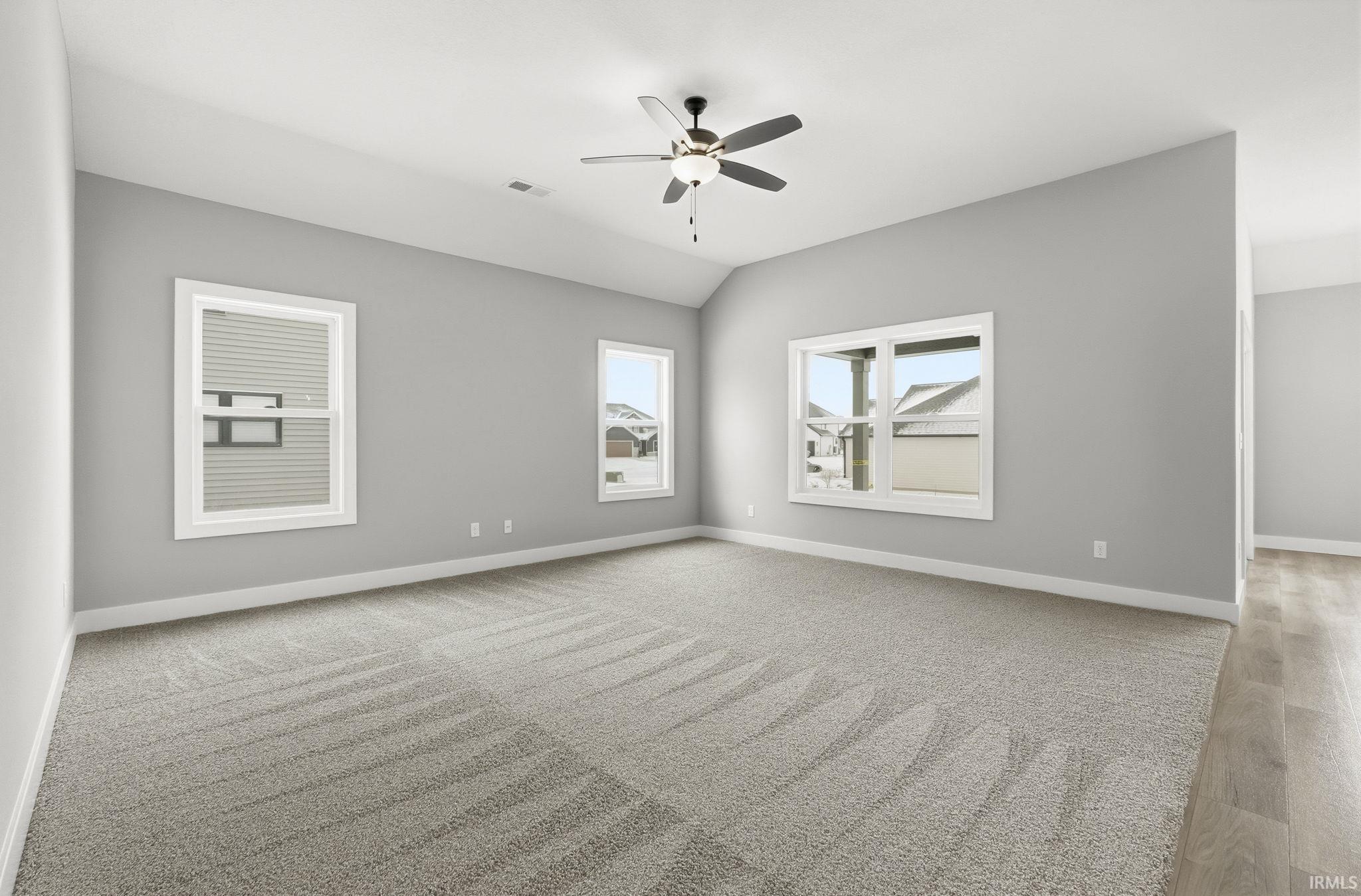 Empty room with vaulted ceiling and ceiling fan