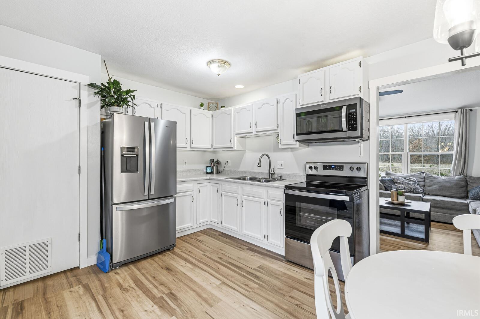 Kitchen featuring appliances with stainless steel finishes, white cabinets, light countertops, light wood-style flooring, and recessed lighting