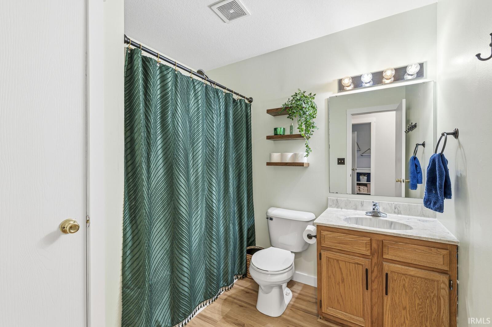 Full bath with vanity, a shower with shower curtain, and light wood finished floors
