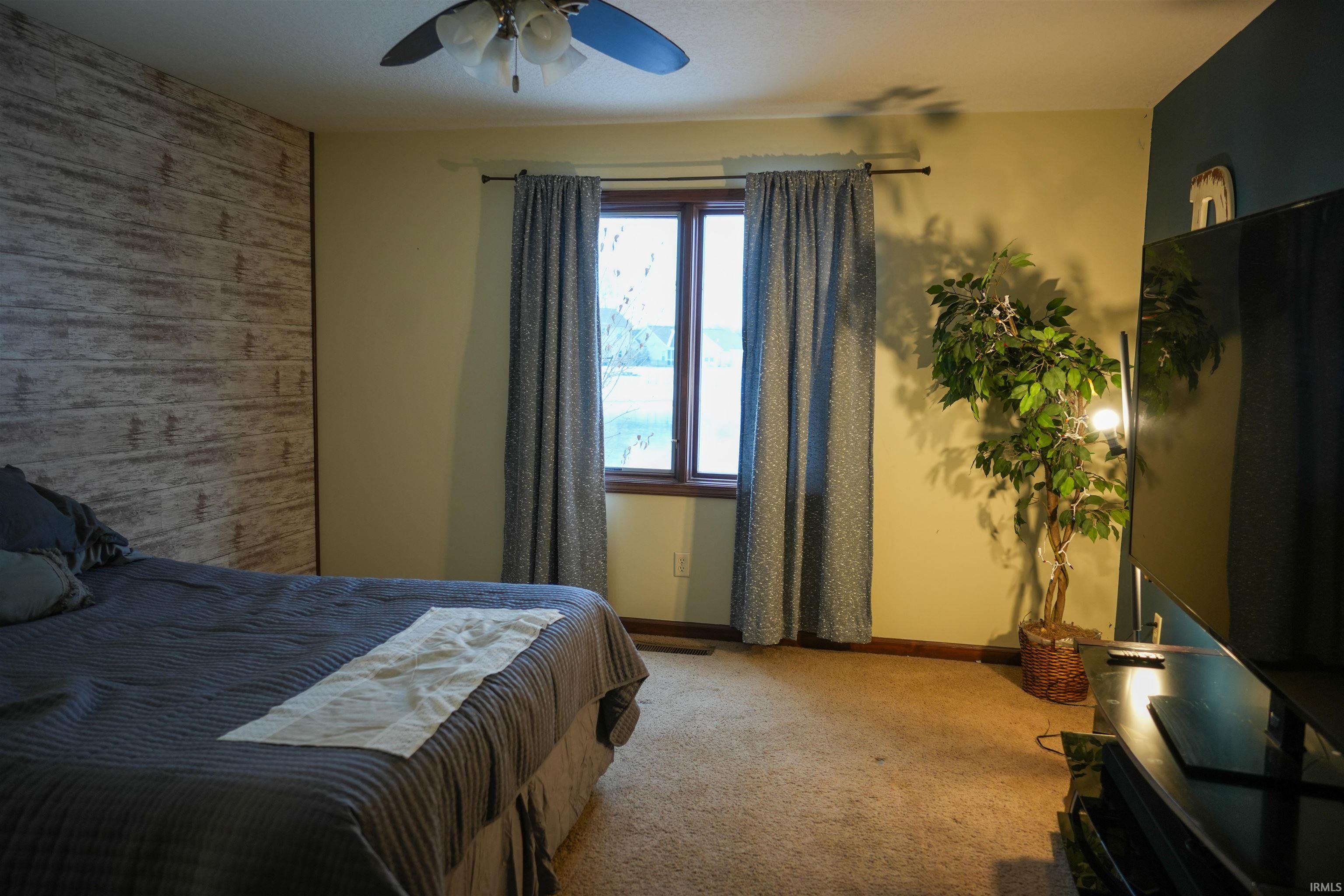 Bedroom featuring carpet, ceiling fan, and an accent wall