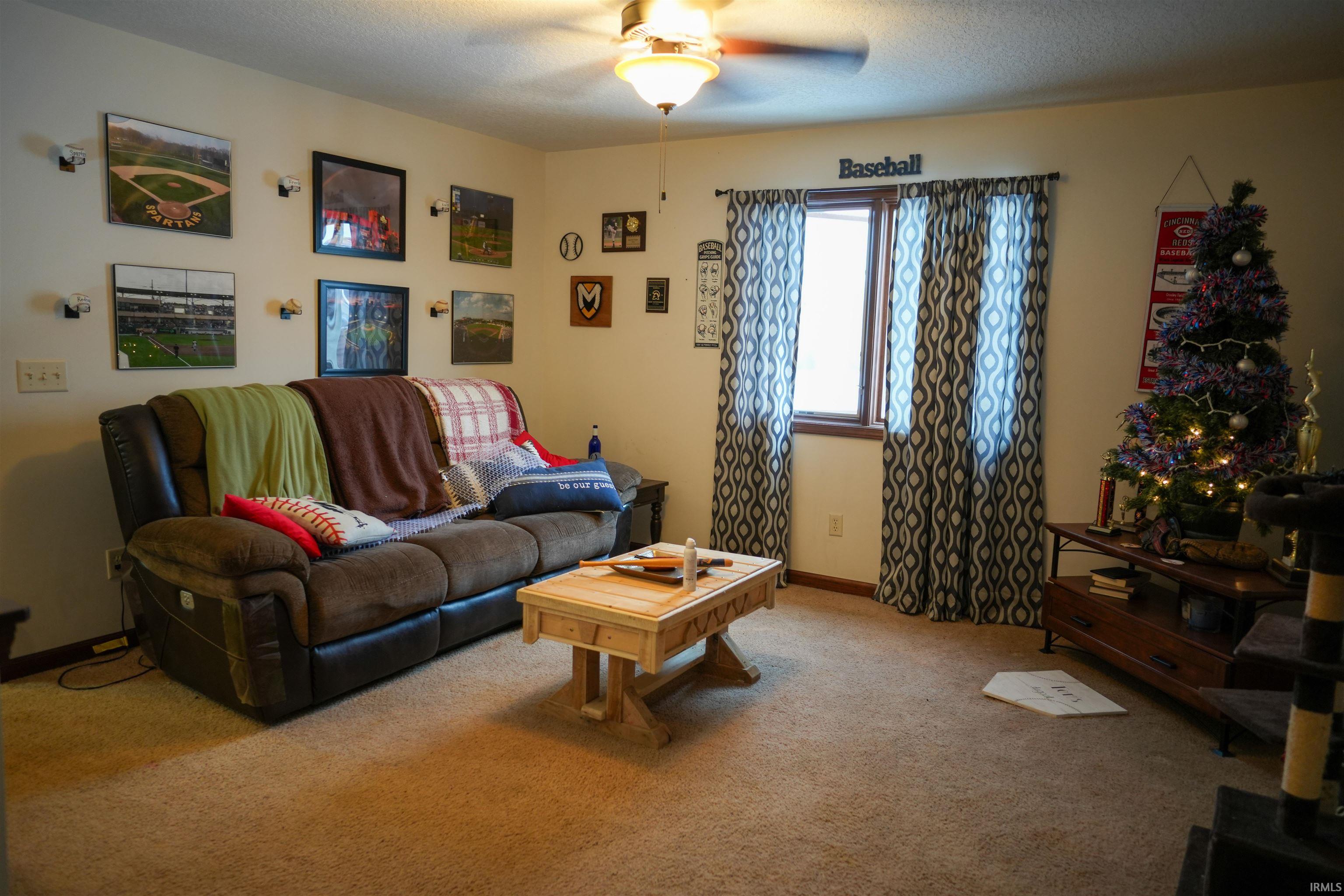 Carpeted living room featuring ceiling fan and a textured ceiling
