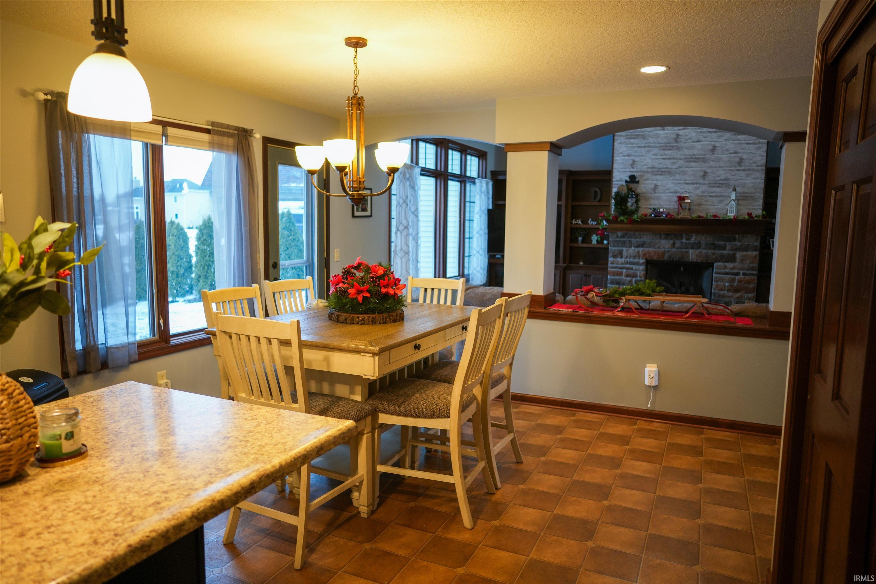 Dining room with a stone fireplace, a chandelier, a textured ceiling, built in features, and recessed lighting